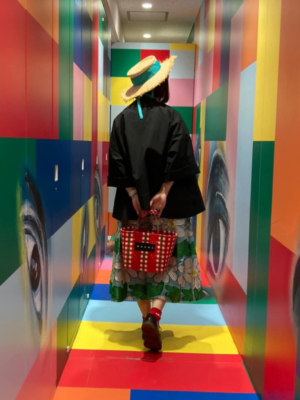 ブラック系のチェスターコート、ホワイト系のTシャツ/カットソー、ブルー系のスカートを着用したレディースの夏コーディネートの3枚目の写真