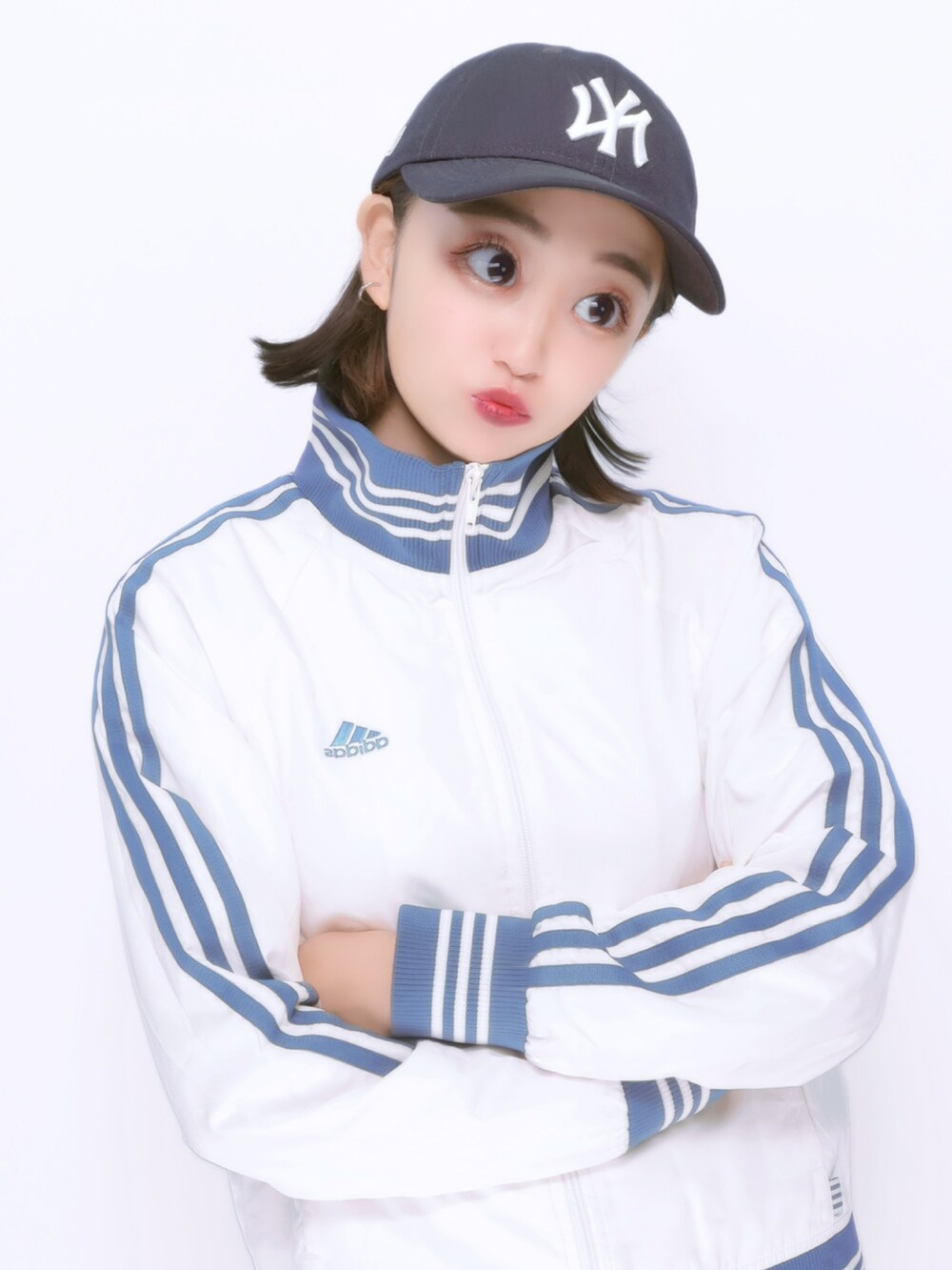 ホワイト系のブルゾン、ブルー系のデニムパンツ、ブルー系のキャップを着用したレディースの秋コーディネートの2枚目の写真