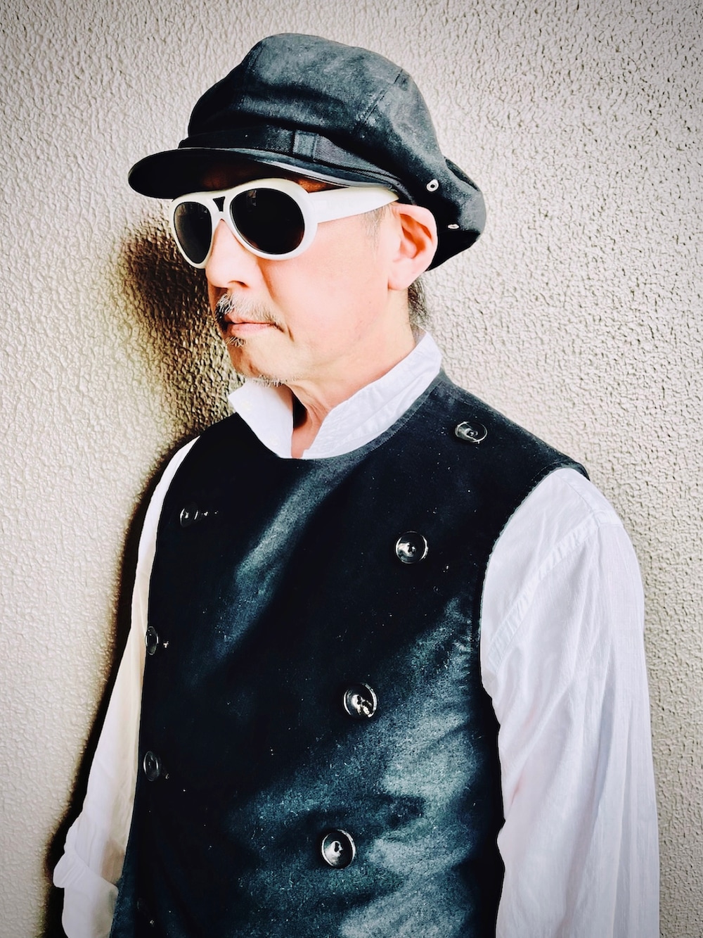 ブラック系のベスト、ブラック系のチノパンツ、ブラック系のブーツを着用したメンズの春コーディネートの4枚目の写真