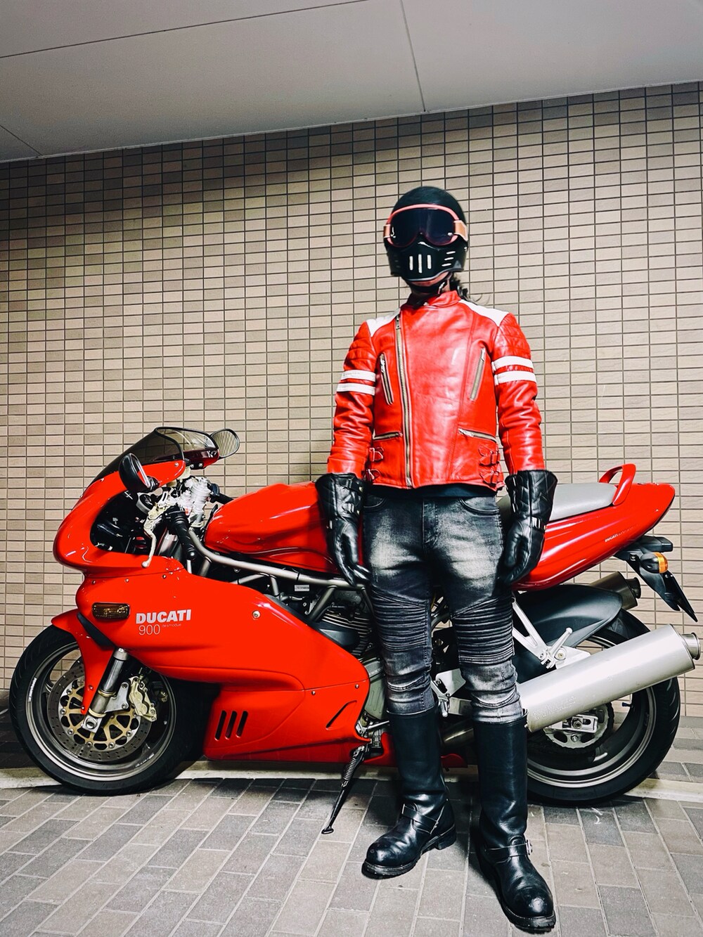 レッド系のライダースジャケット、ブラック系のデニムパンツ、ブラック系のブーツを着用したメンズの冬コーディネートの3枚目の写真