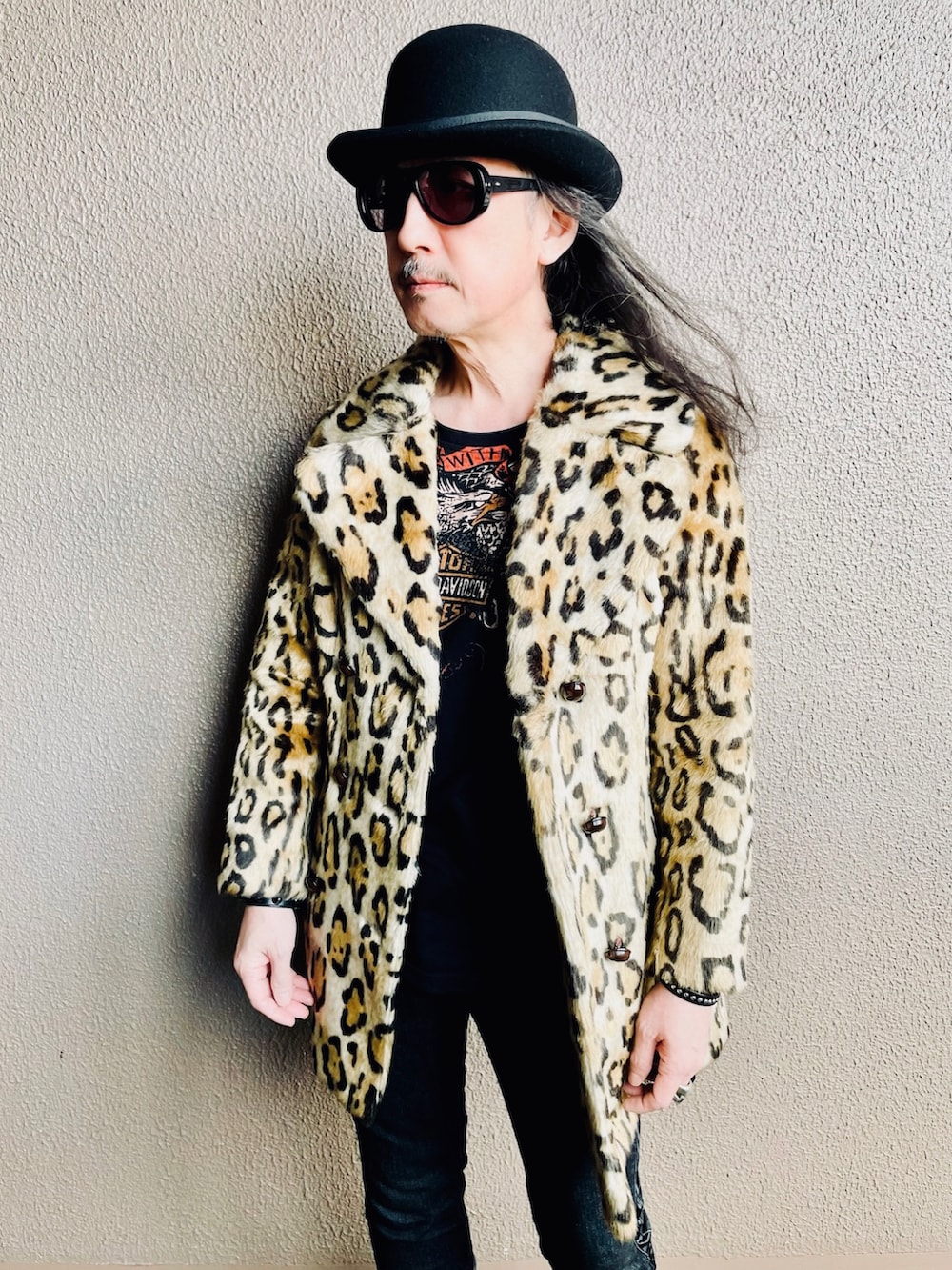 イエロー系のピーコート、ブラック系のデニムパンツ、ブラック系のブーツを着用したメンズの春コーディネートの2枚目の写真