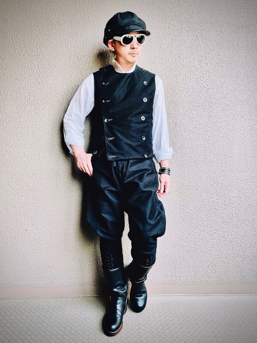 ブラック系のベスト、ブラック系のチノパンツ、ブラック系のブーツを着用したメンズの春コーディネートの3枚目の写真