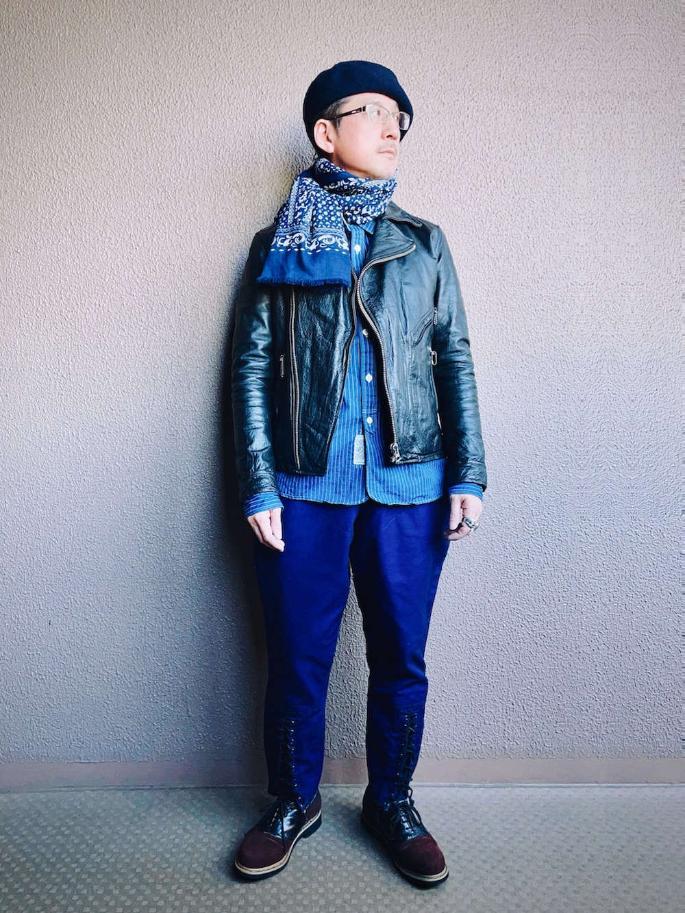 ブラック系のライダースジャケット、ブルー系のチノパンツ、ブラウン系のドレスシューズを着用したメンズの冬コーディネートの2枚目の写真