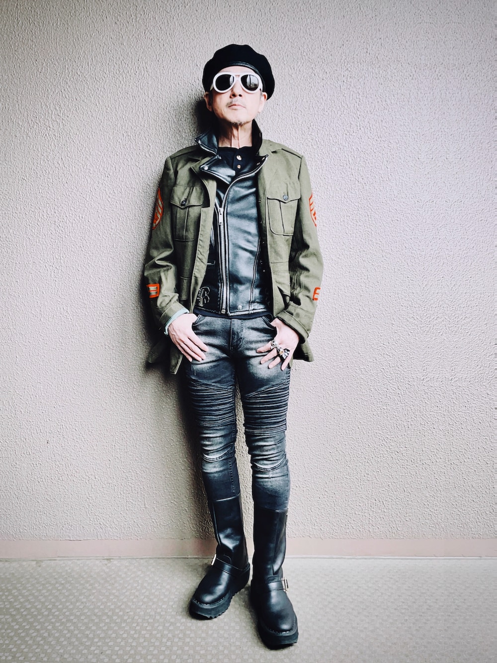 グリーン系のミリタリージャケット、ブラック系のライダースジャケット、ブラック系のデニムパンツを着用したメンズの冬コーディネートの2枚目の写真