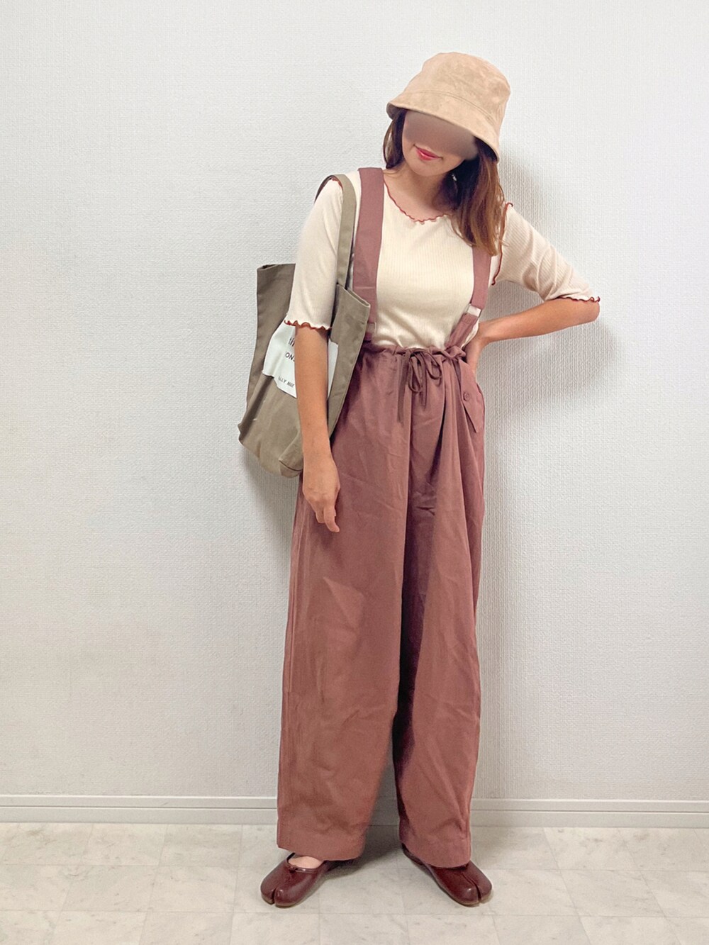 ホワイト系のTシャツ/カットソー、ブラウン系のチノパンツ、ベージュ系のトートバッグを着用したレディースの夏コーディネートの2枚目の写真