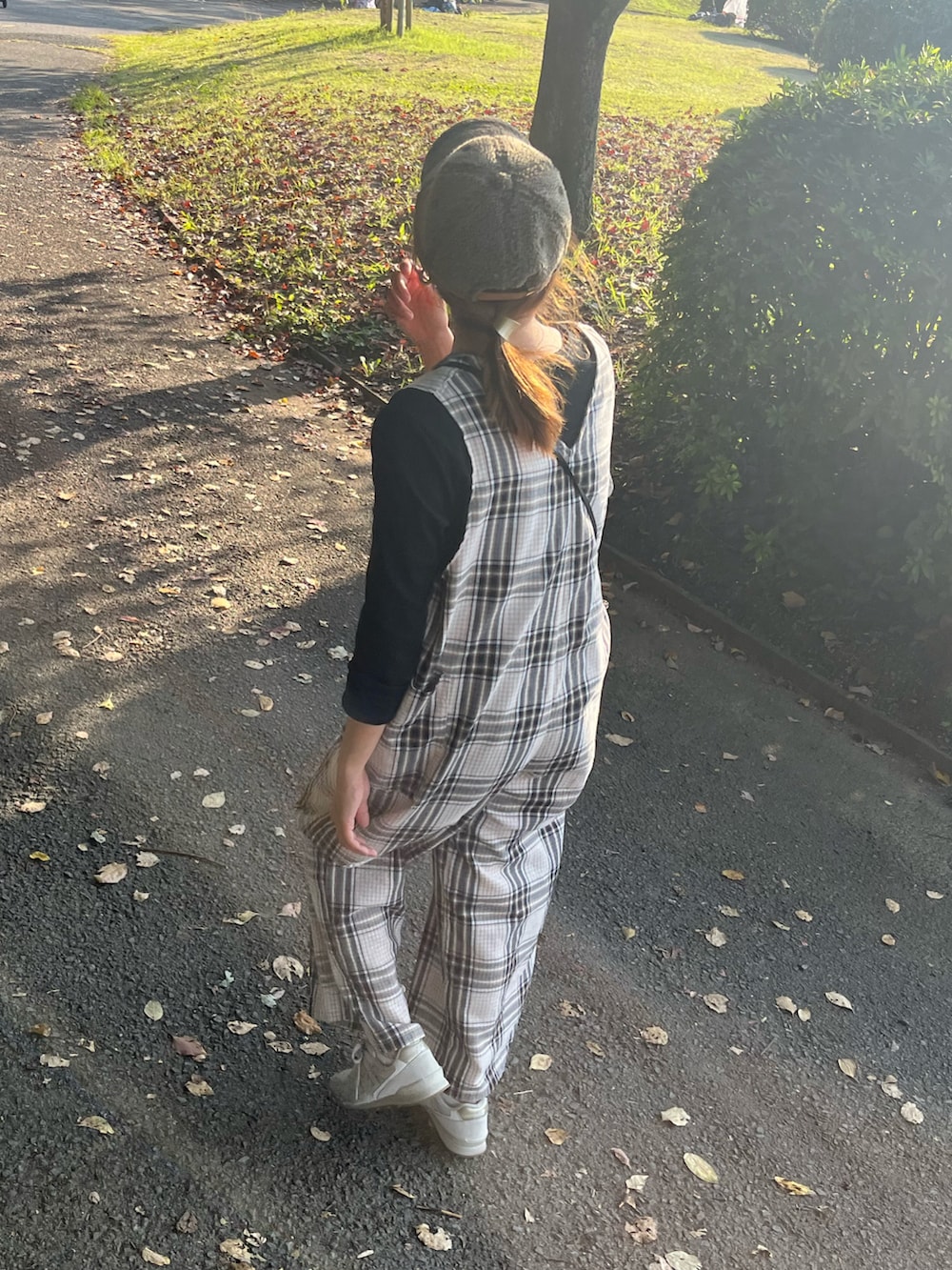 ベージュ系のオールインワン・サロペット、ホワイト系のスニーカー、グリーン系のキャップを着用したレディースの秋コーディネートの4枚目の写真