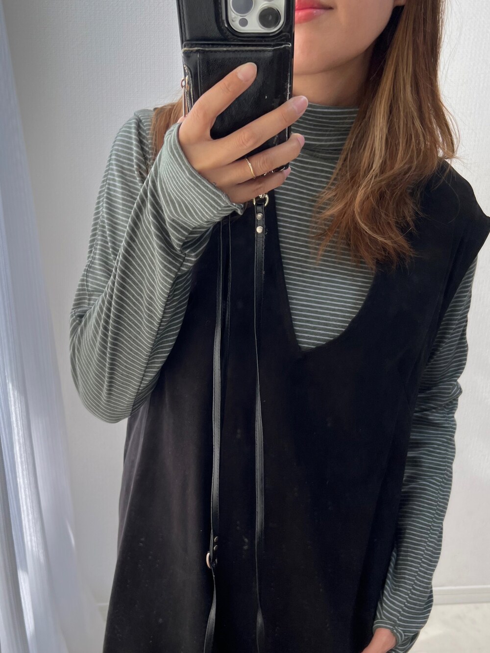 ブラック系のジャンパースカート、ホワイト系のスニーカーを着用したレディースの秋コーディネートの3枚目の写真