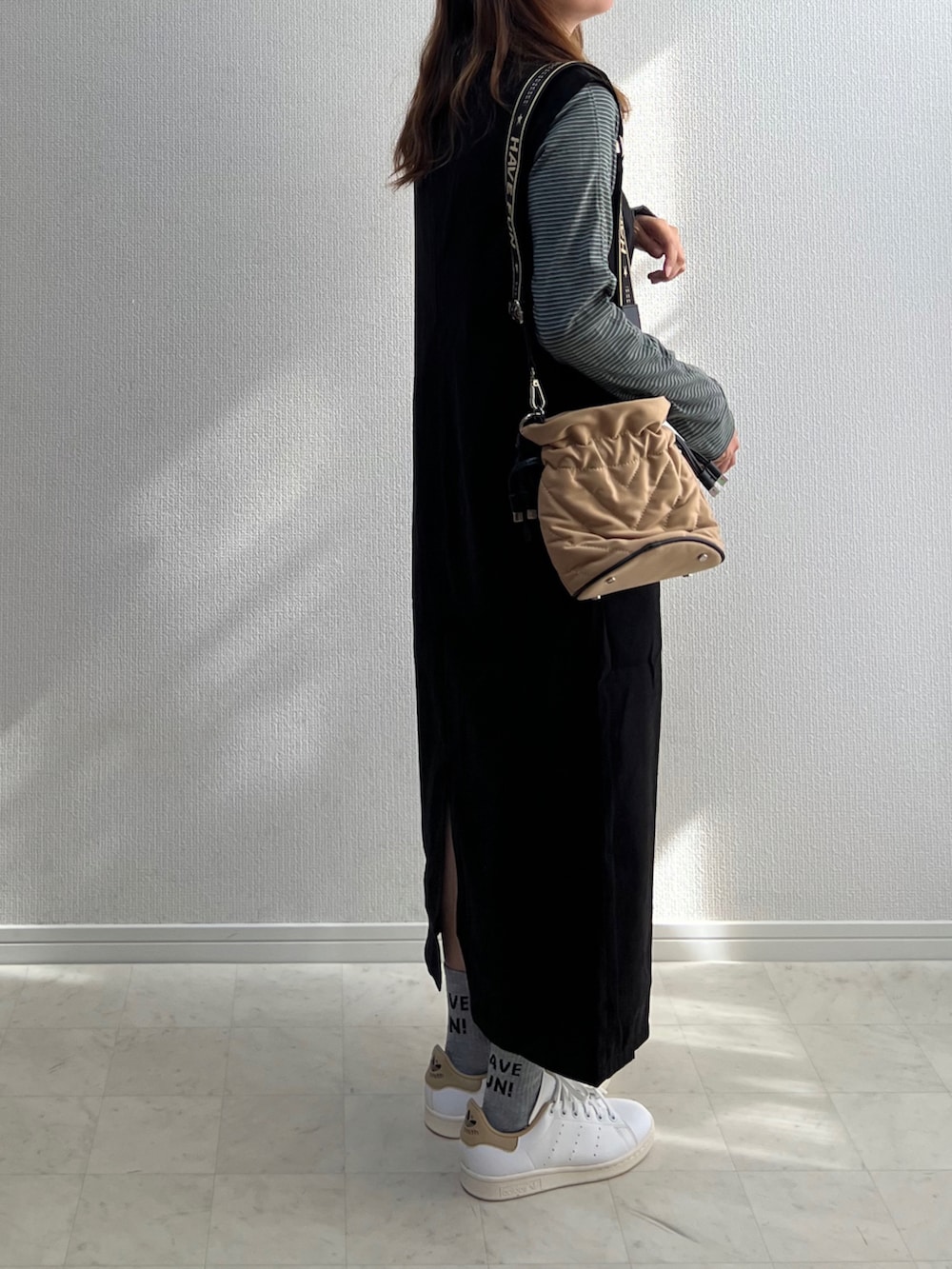 ブラック系のジャンパースカート、ホワイト系のスニーカーを着用したレディースの秋コーディネートの2枚目の写真