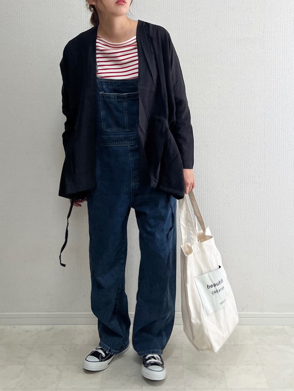 ブラック系のカーディガン/ボレロ、ブラック系のスニーカー、ブルー系のサロペット/オーバーオールを着用したレディースの春コーディネートの4枚目の写真