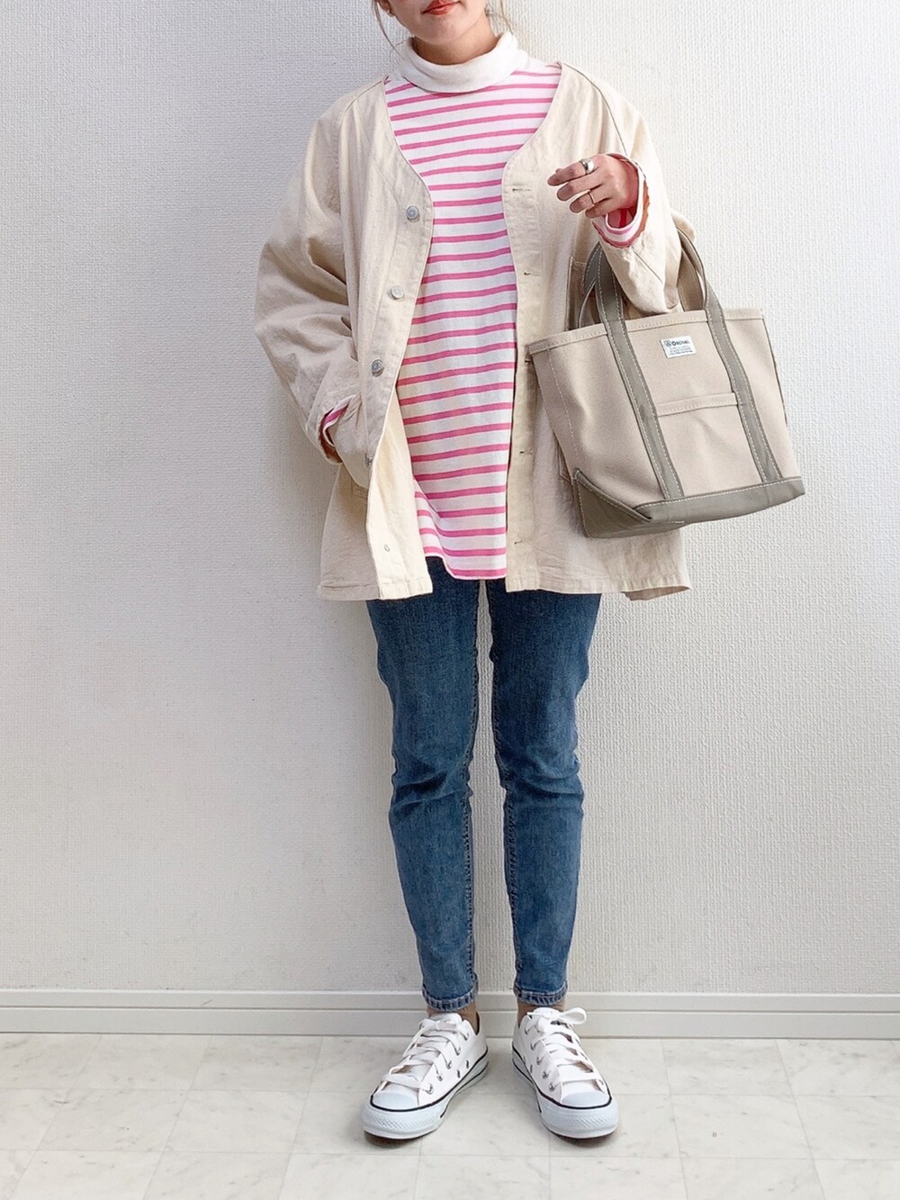 ホワイト系のブルゾン、グリーン系のトートバッグ、ピンク系のトップスを着用したレディースの冬コーディネートの2枚目の写真