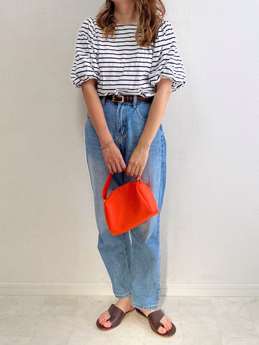 ブラック系のTシャツ/カットソー、オレンジ系のハンドバッグ、ブルー系のデニムパンツを着用したレディースの夏コーディネートの3枚目の写真