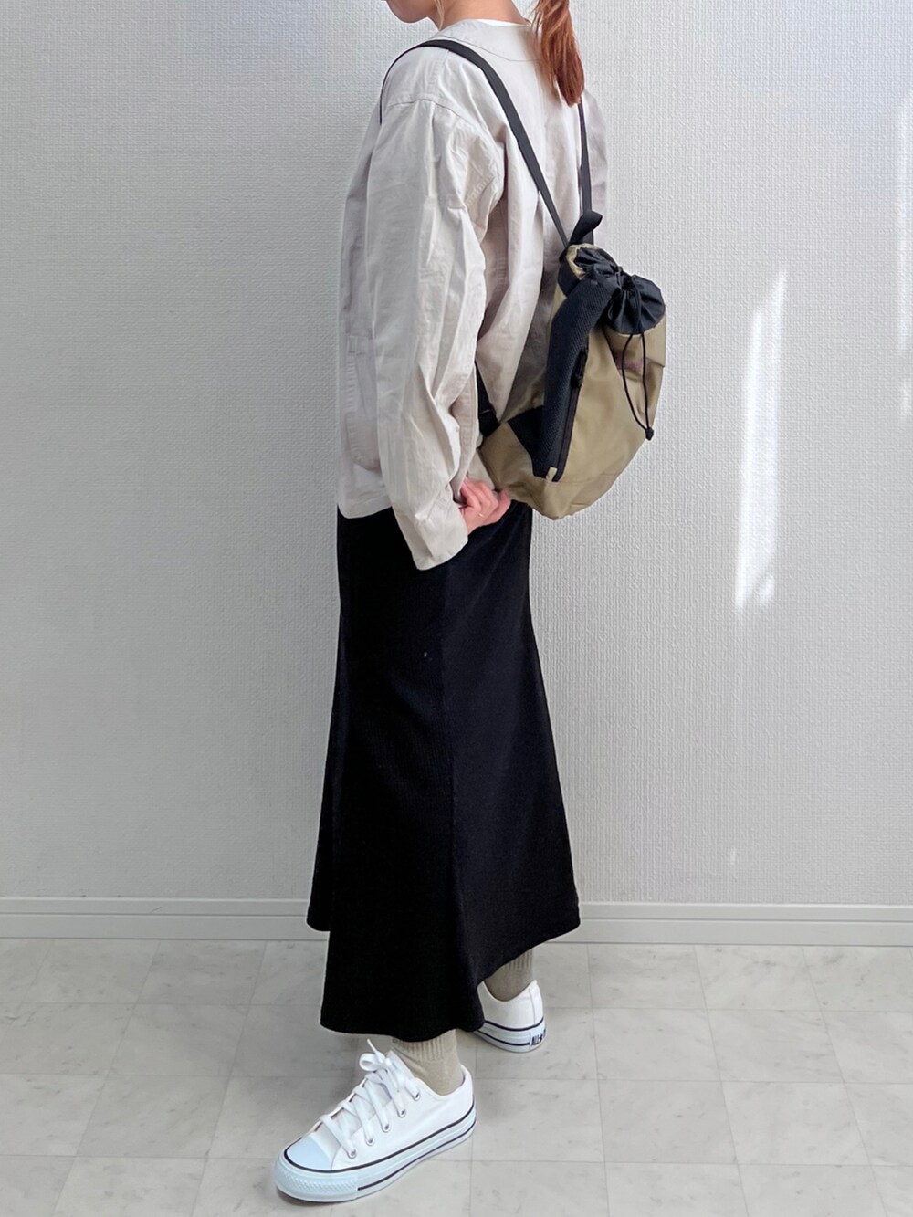 グレー系のノーカラージャケット、ブラック系のスカート、ベージュ系のバックパック/リュックを着用したレディースの春コーディネートの2枚目の写真