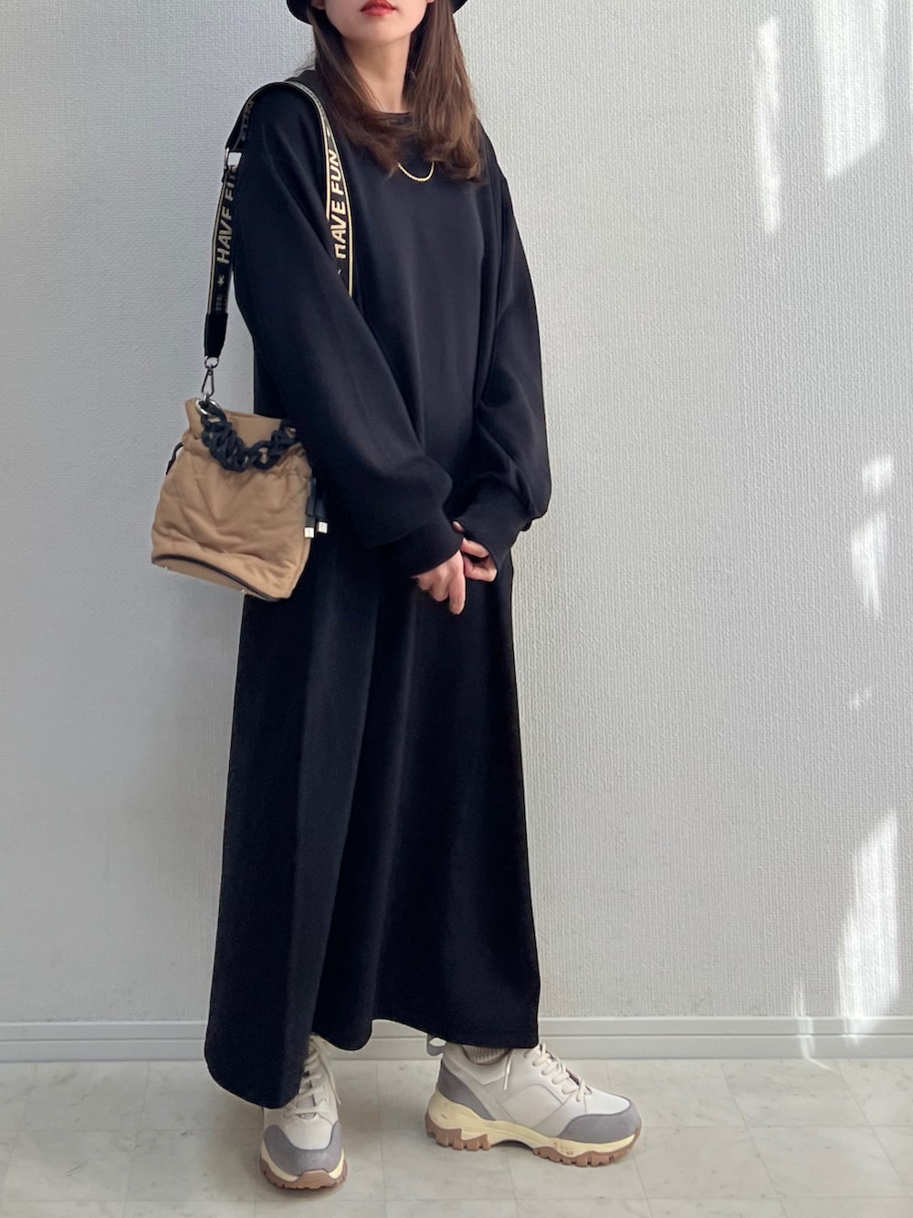 ブラック系のワンピース、ベージュ系のスニーカーを着用したレディースの冬コーディネートの2枚目の写真