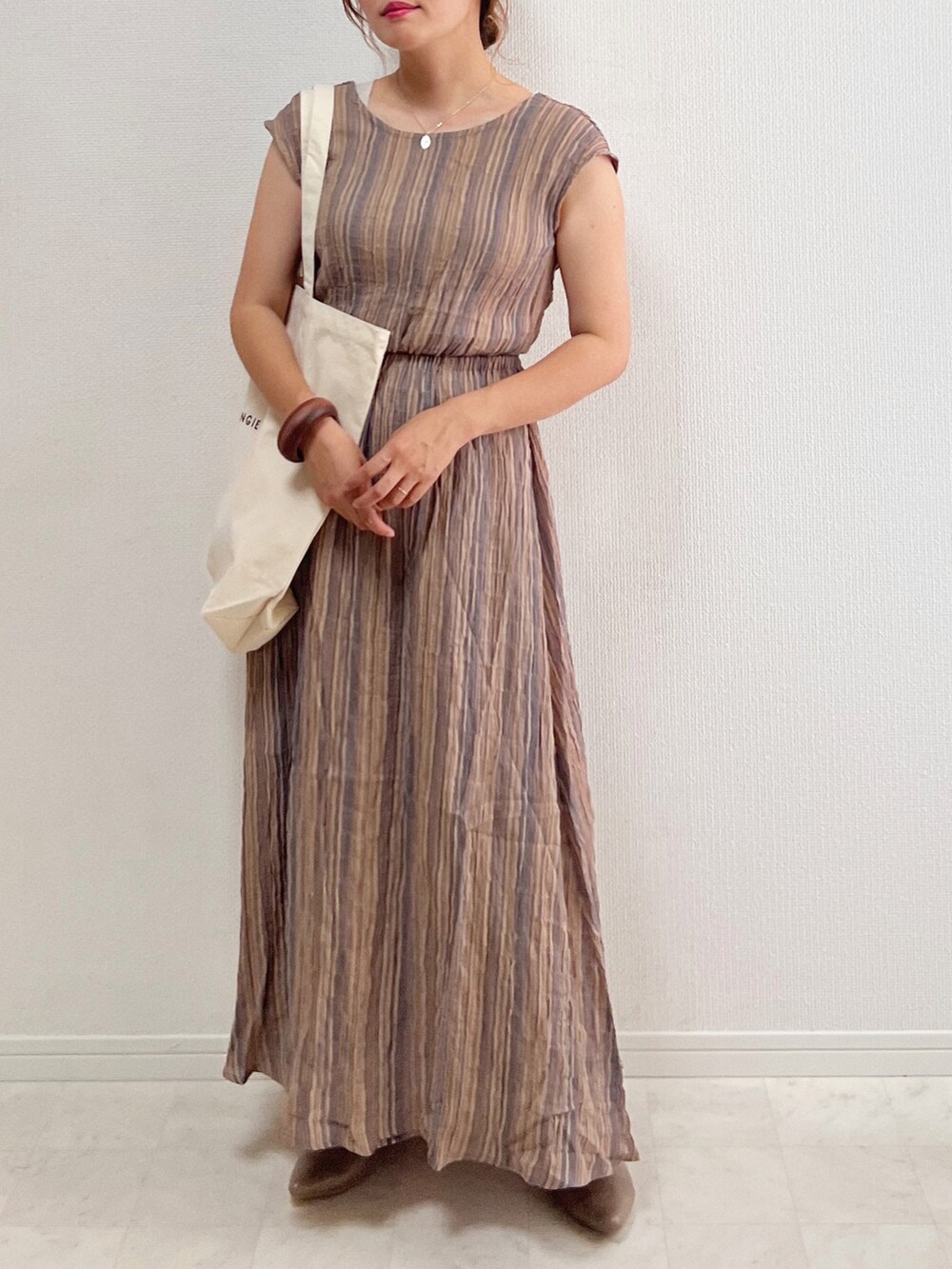 グレー系のワンピース、ホワイト系のトートバッグ、ベージュ系のシューズを着用したレディースの春コーディネートの2枚目の写真