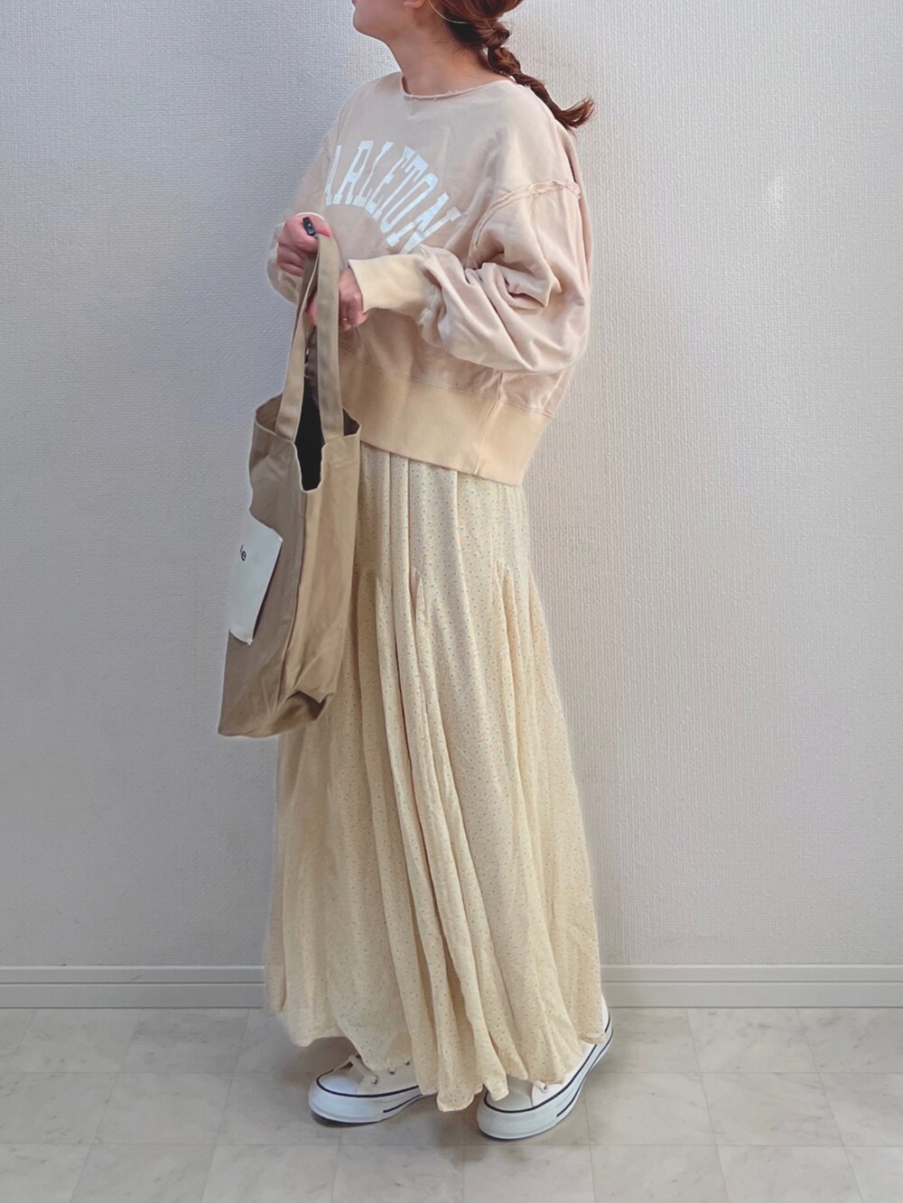 イエロー系のスカート、ベージュ系のスウェット、ベージュ系のトートバッグを着用したレディースの春コーディネートの2枚目の写真