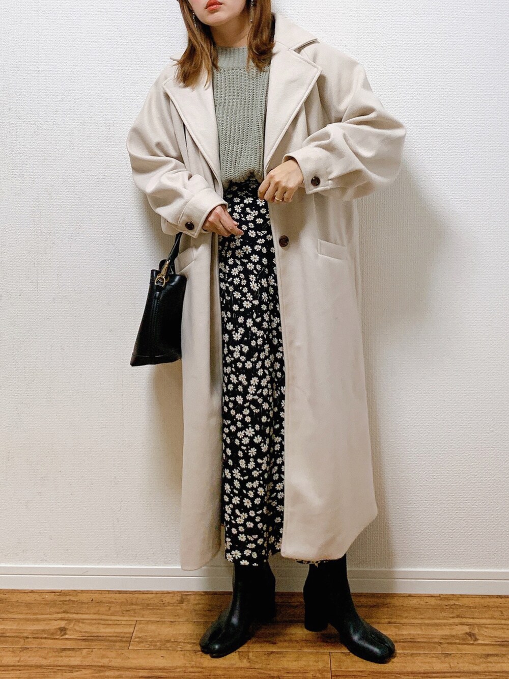 ホワイト系のチェスターコート、グレー系のニット/セーター、ブラック系のショルダーバッグを着用したレディースの冬コーディネートの2枚目の写真