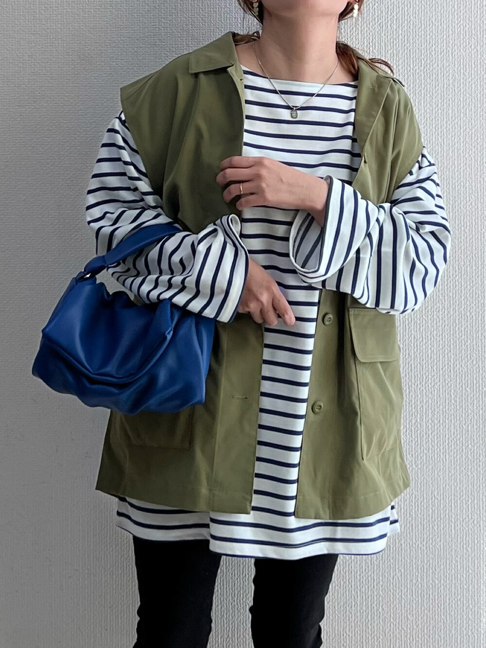 グリーン系のベスト、ブルー系のトップス、ブルー系のショルダーバッグを着用したレディースの春コーディネートの3枚目の写真