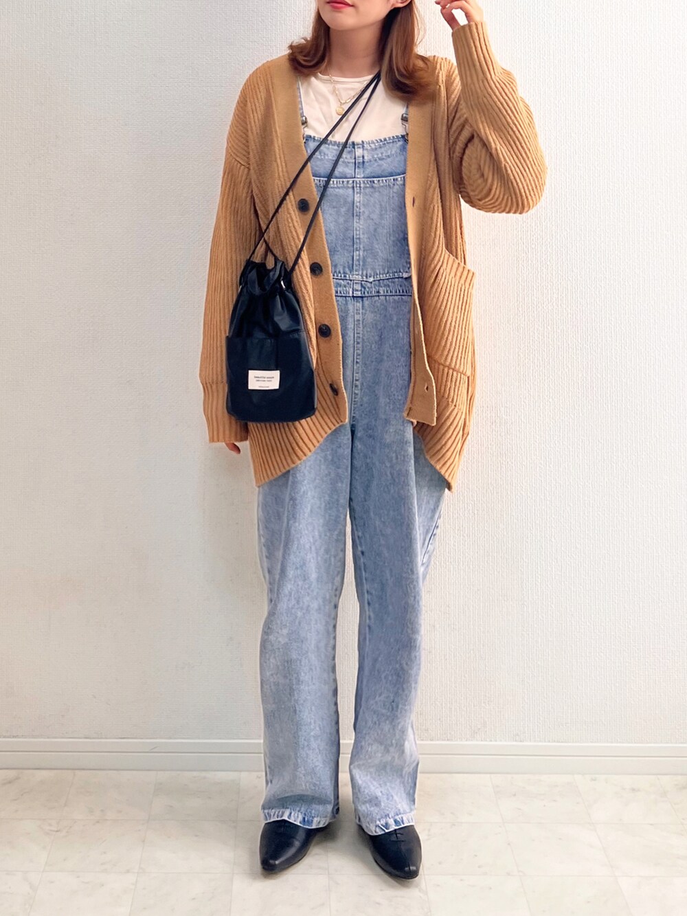 イエロー系のニット/セーター、ブルー系のサロペット/オーバーオール、ブラック系のドレスシューズを着用したレディースの秋コーディネートの2枚目の写真