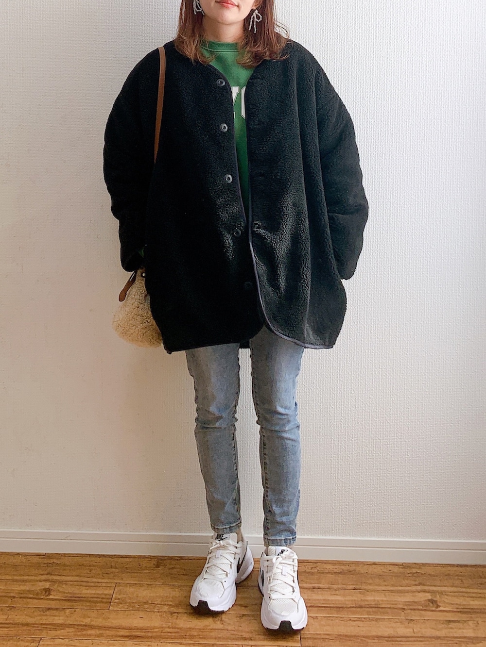 ブラック系のブルゾン、グリーン系のスウェット、ブルー系のデニムパンツを着用したレディースの秋コーディネートの3枚目の写真