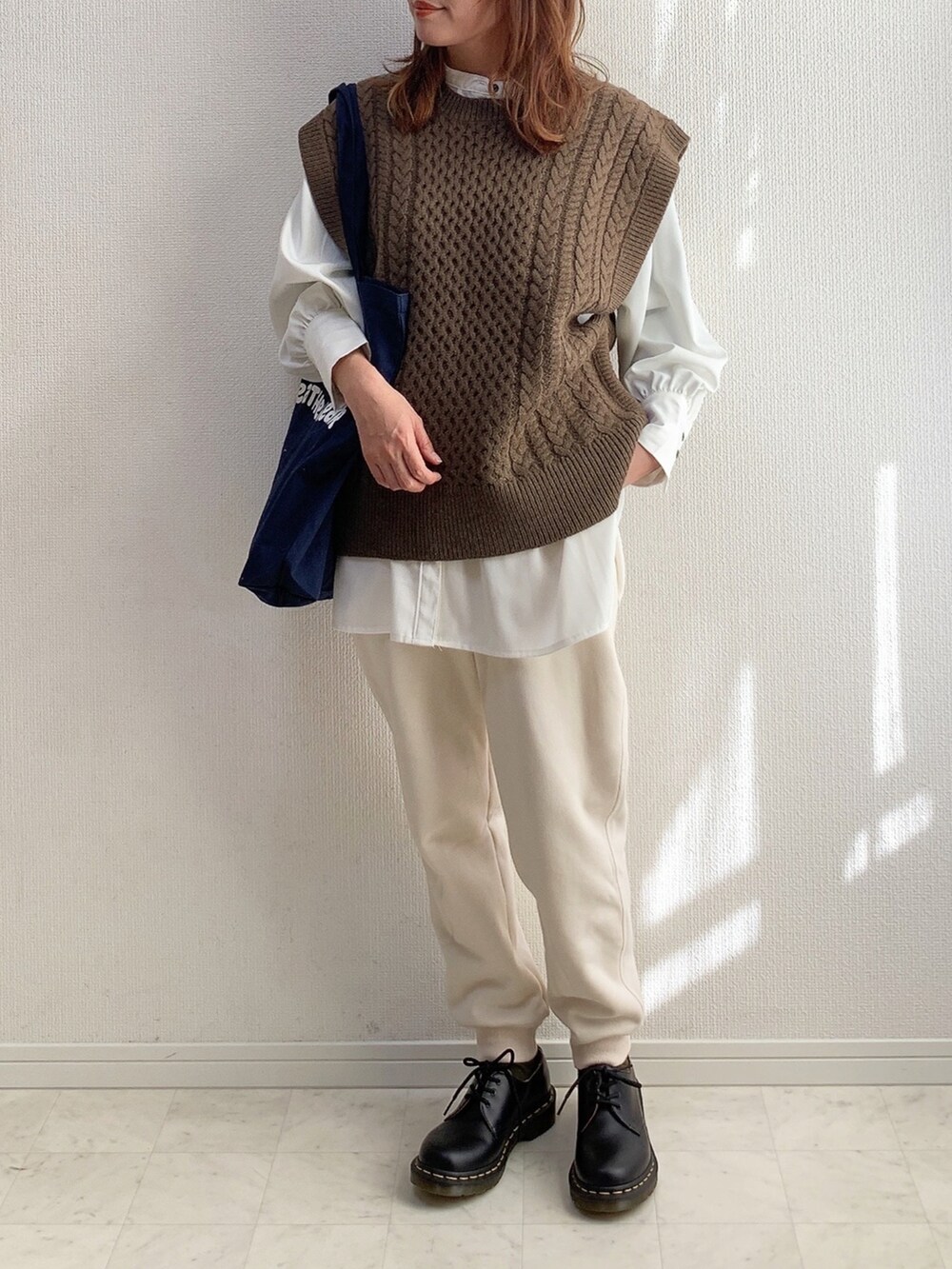 ブラウン系のベスト、ホワイト系のスウェットパンツ、ブラック系のドレスシューズを着用したレディースの冬コーディネートの2枚目の写真