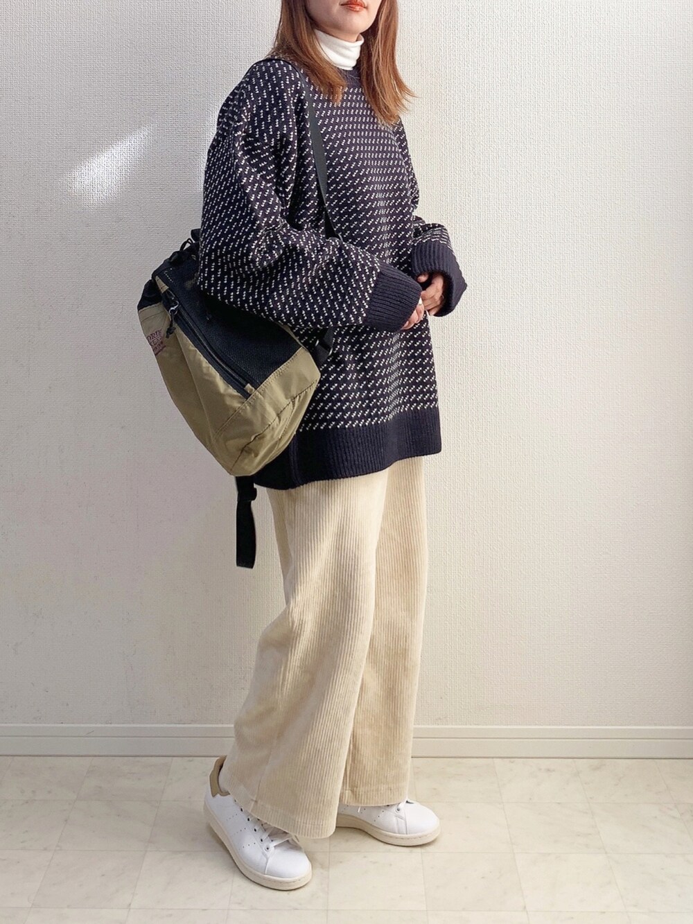 ブルー系のニット/セーター、ベージュ系のバックパック/リュック、ホワイト系のその他パンツを着用したレディースの冬コーディネートの2枚目の写真