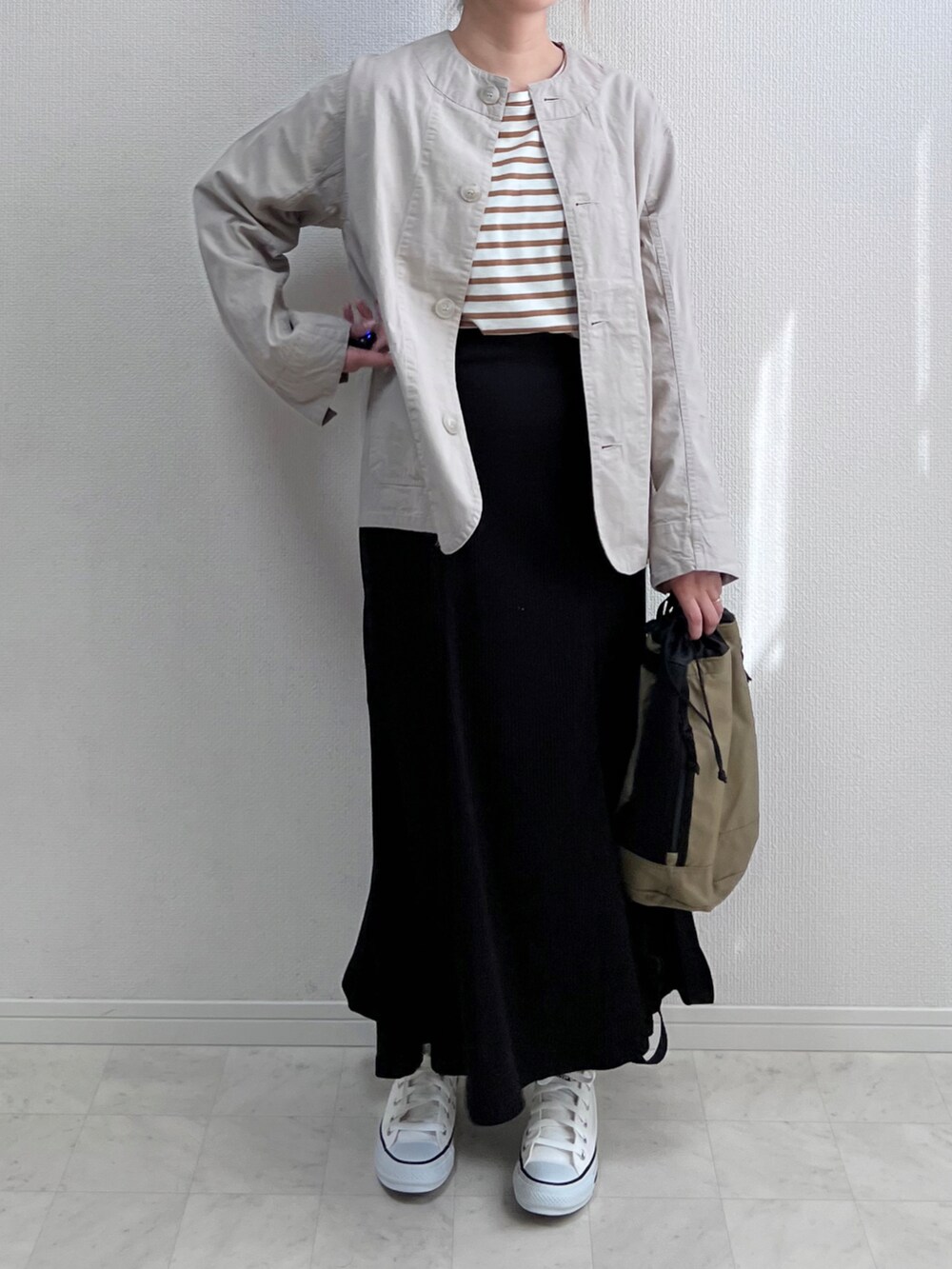 グレー系のノーカラージャケット、ブラック系のスカート、ベージュ系のバックパック/リュックを着用したレディースの春コーディネートの3枚目の写真