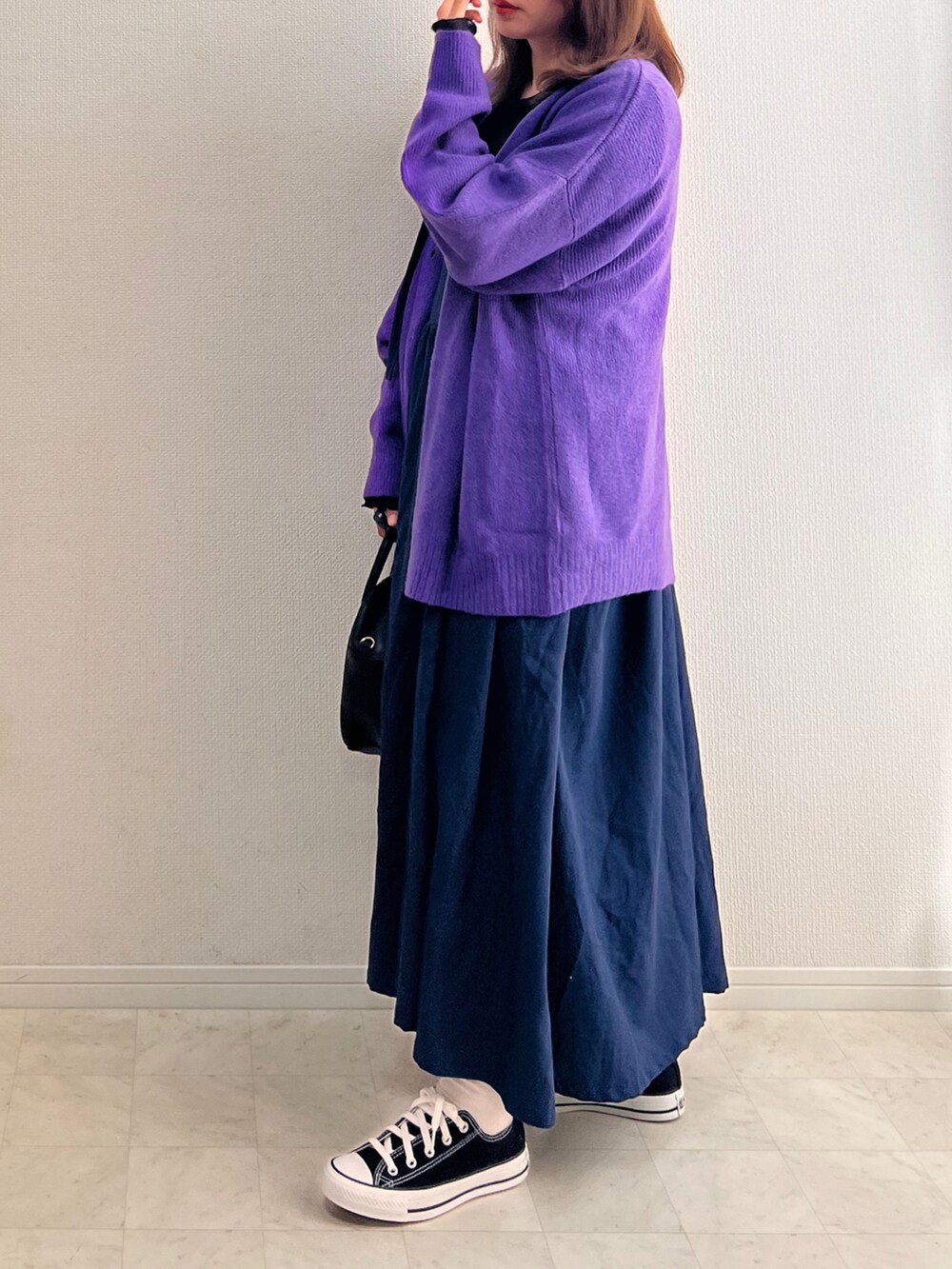 ブルー系のジャンパースカート、パープル系のカーディガン/ボレロ、ブラック系のスニーカーを着用したレディースの秋コーディネートの2枚目の写真