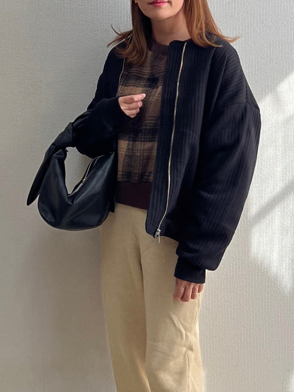 ブラック系のブルゾン、ホワイト系のその他パンツ、ブラック系のバッグを着用したレディースの秋コーディネートの3枚目の写真