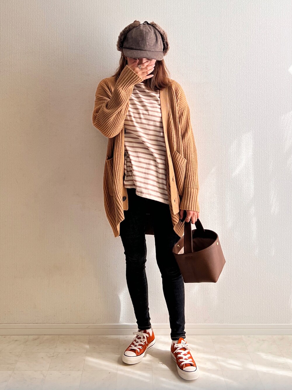 イエロー系のニット/セーター、ブラウン系のバッグ、ブラウン系のTシャツ/カットソーを着用したレディースの秋コーディネートの2枚目の写真