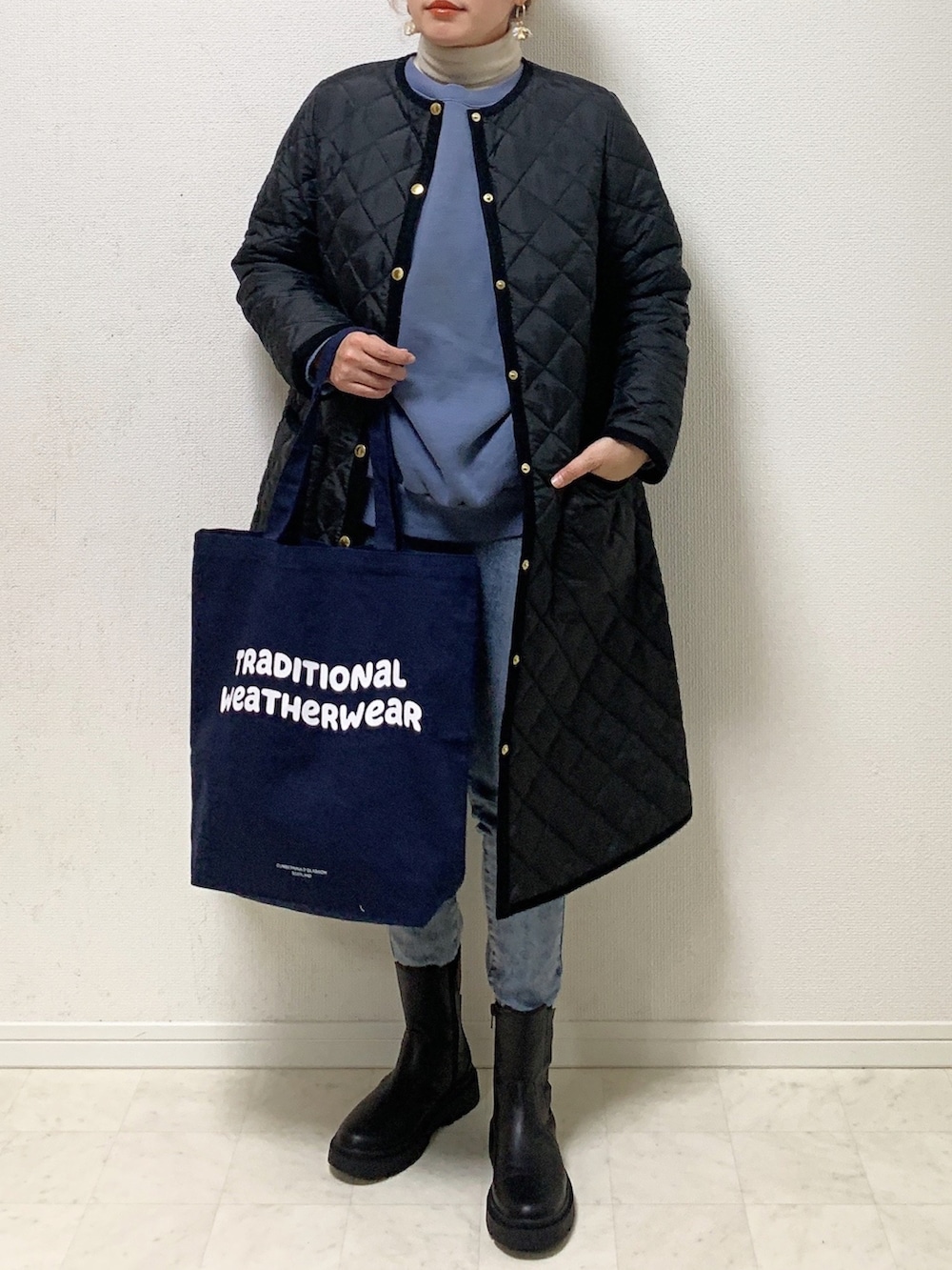 ブルー系のノーカラーコート、ブルー系のトートバッグ、ブルー系のデニムパンツを着用したレディースの冬コーディネートの2枚目の写真