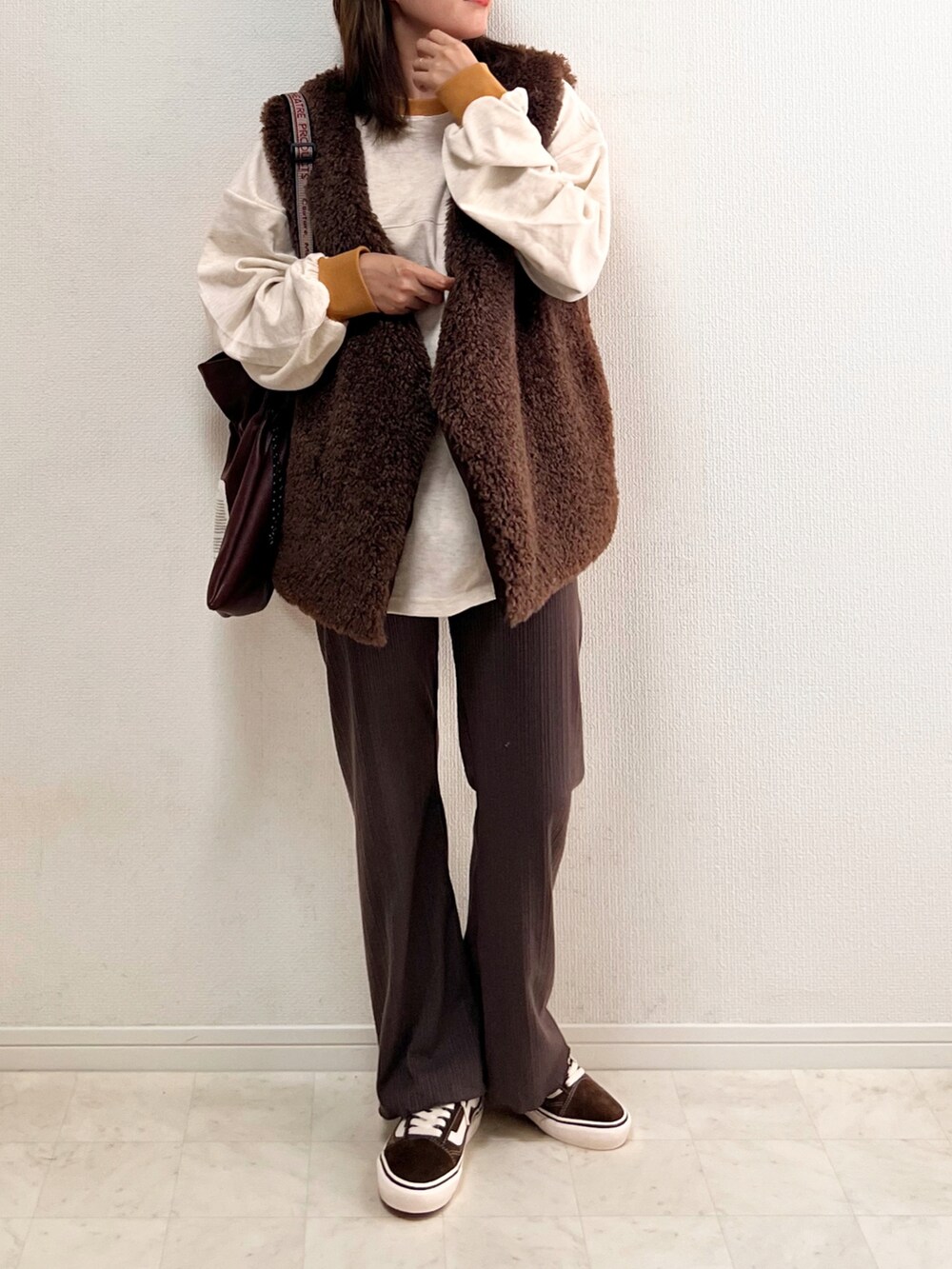 ベージュ系のスウェット、ブラウン系のベスト、ブラウン系のその他パンツを着用したレディースの秋コーディネートの2枚目の写真