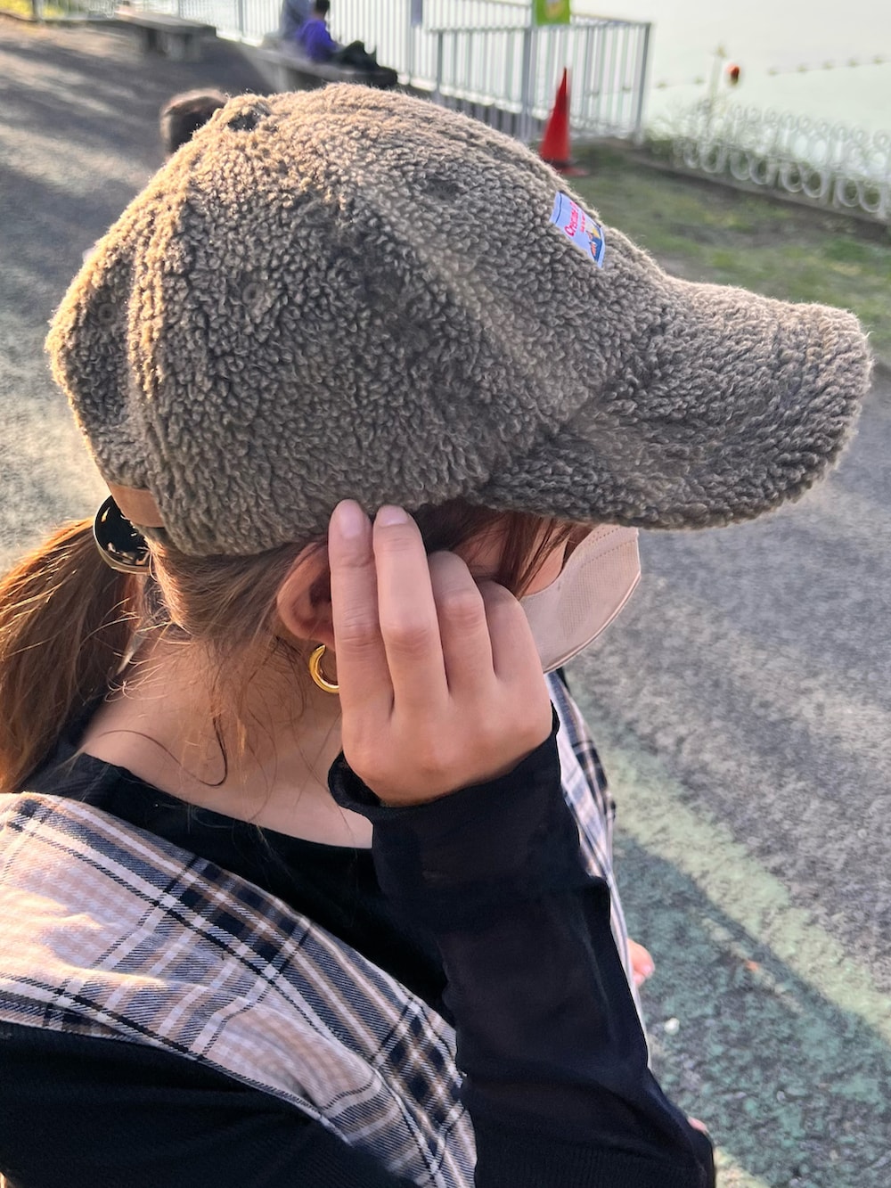 ベージュ系のオールインワン・サロペット、ホワイト系のスニーカー、グリーン系のキャップを着用したレディースの秋コーディネートの3枚目の写真