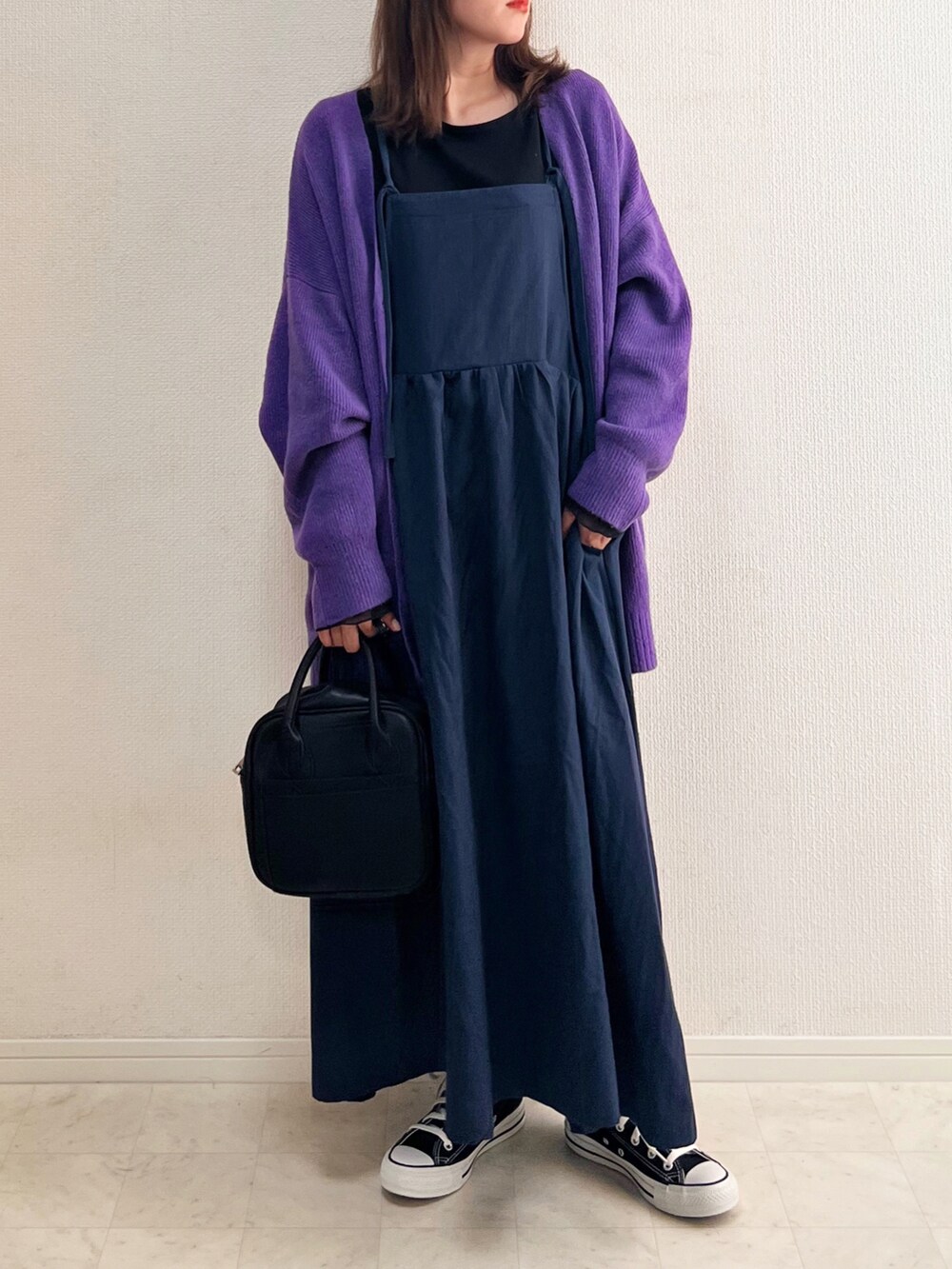 ブルー系のジャンパースカート、パープル系のカーディガン/ボレロ、ブラック系のスニーカーを着用したレディースの秋コーディネートの3枚目の写真