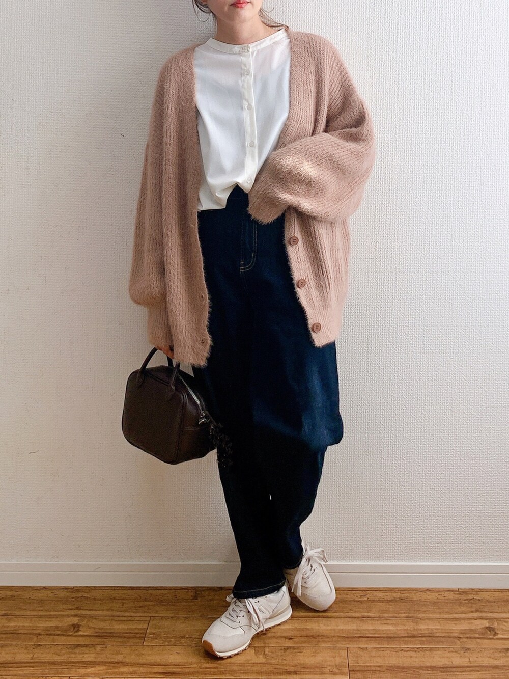 ピンク系のカーディガン/ボレロ、ブルー系のデニムパンツ、ブラウン系のボストンバッグを着用したレディースの秋コーディネートの2枚目の写真