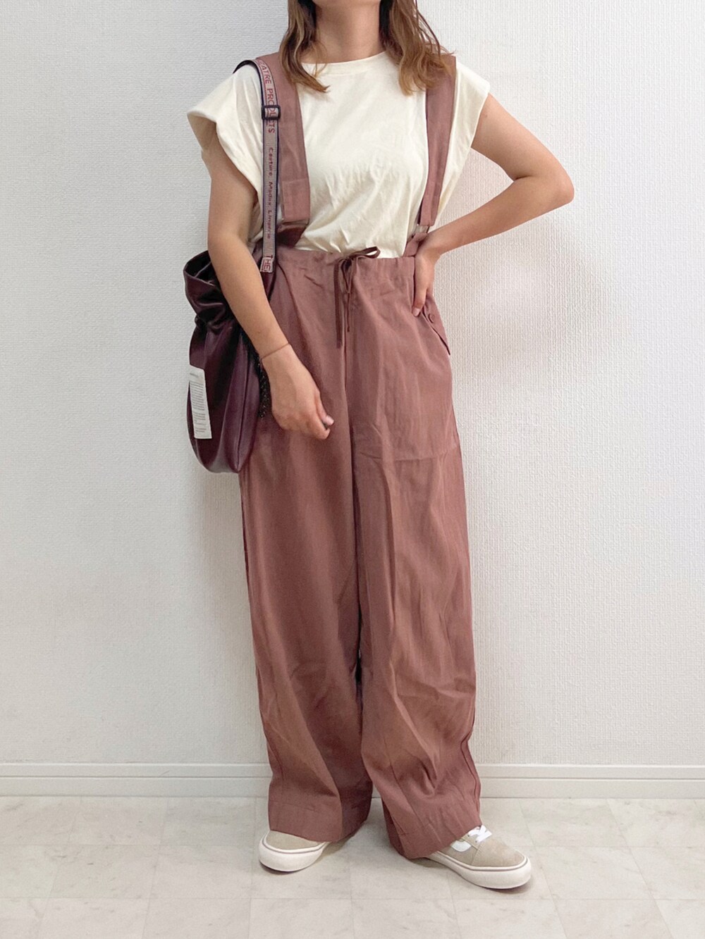 ブラウン系のチノパンツ、ブラウン系のショルダーバッグ、ベージュ系のスニーカーを着用したレディースの夏コーディネートの2枚目の写真