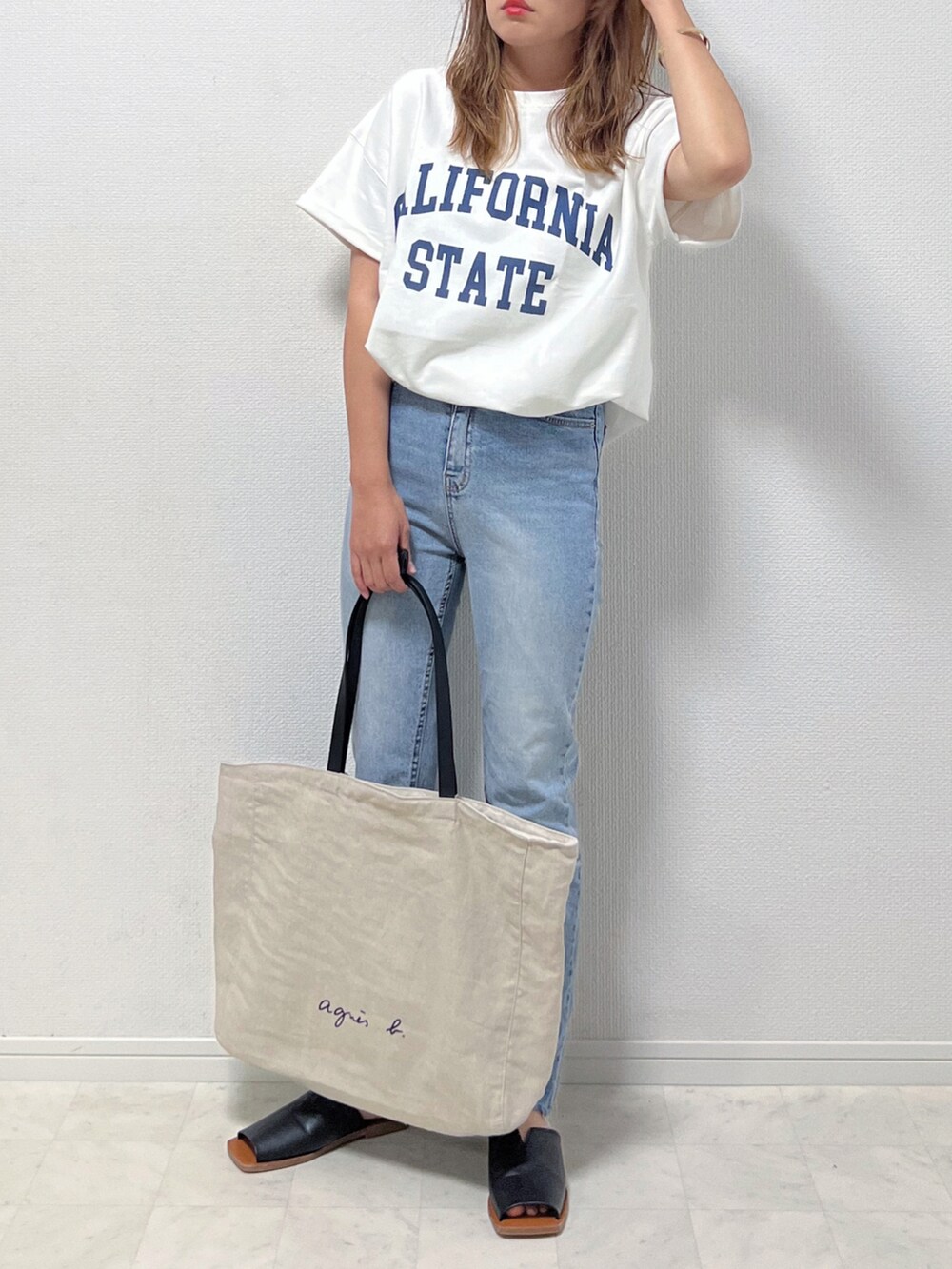 ホワイト系のTシャツ/カットソー、ブルー系のデニムパンツ、ブラック系のサンダルを着用したレディースの春コーディネートの3枚目の写真