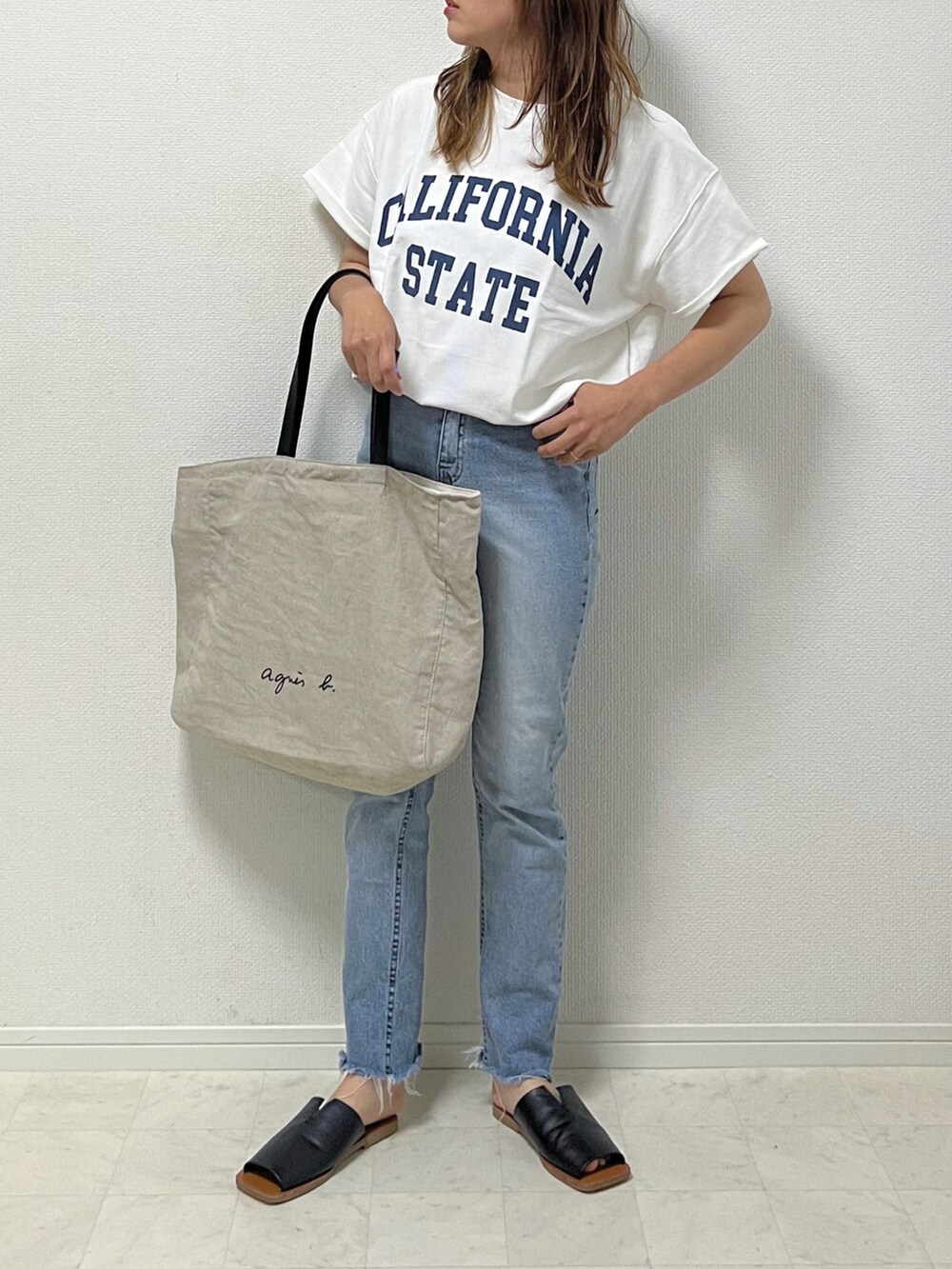 ホワイト系のTシャツ/カットソー、ブルー系のデニムパンツ、ブラック系のサンダルを着用したレディースの春コーディネートの2枚目の写真