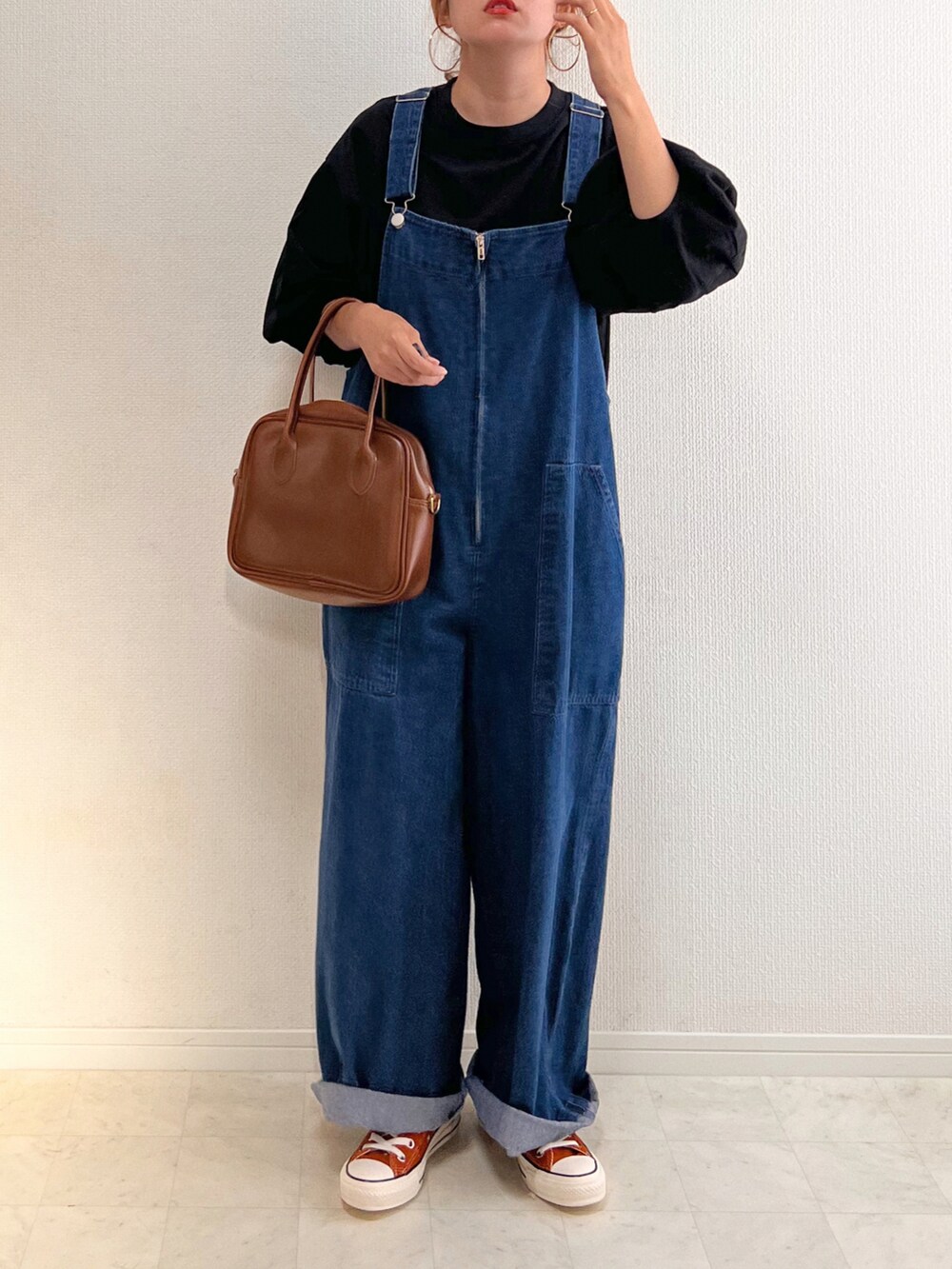 ブラック系のTシャツ/カットソー、ブルー系のオールインワン・サロペット、ブラウン系のハンドバッグを着用したレディースの秋コーディネートの2枚目の写真