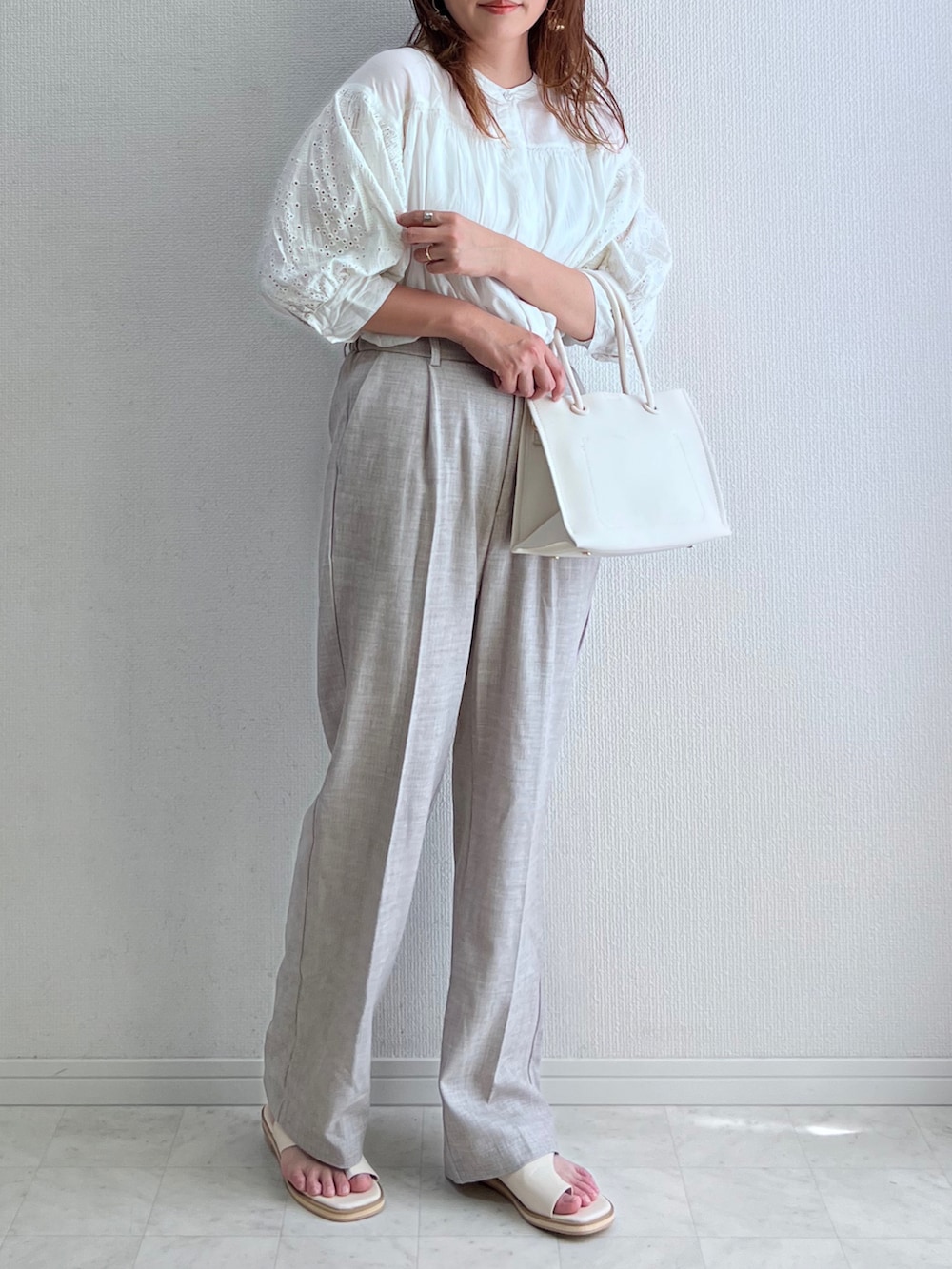 ホワイト系のシャツ/ブラウス、ベージュ系のスラックス、ホワイト系のサンダルを着用したレディースの春コーディネートの2枚目の写真