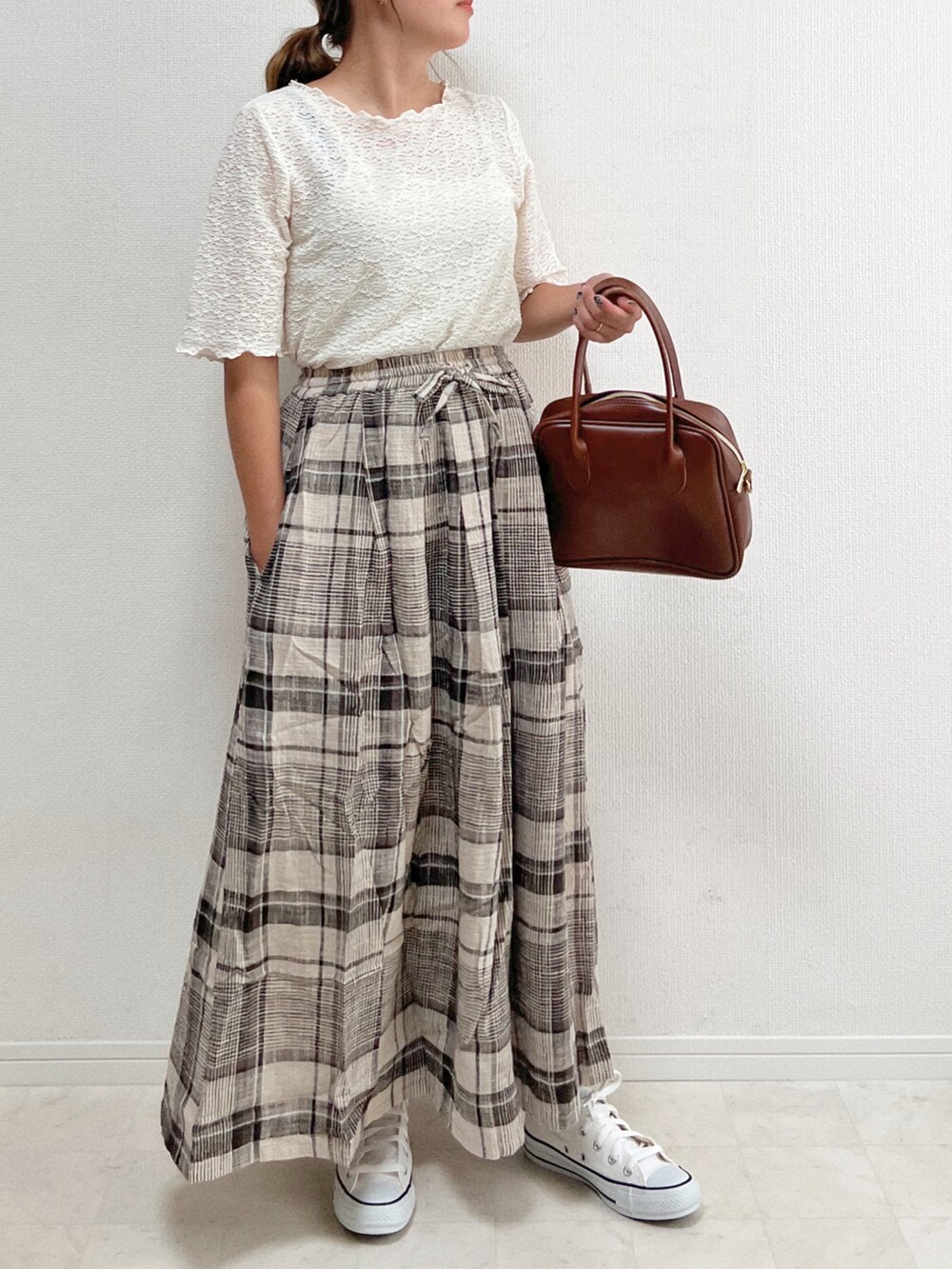 ベージュ系のスカート、ホワイト系のスニーカー、ブラウン系のハンドバッグを着用したレディースの夏コーディネートの2枚目の写真