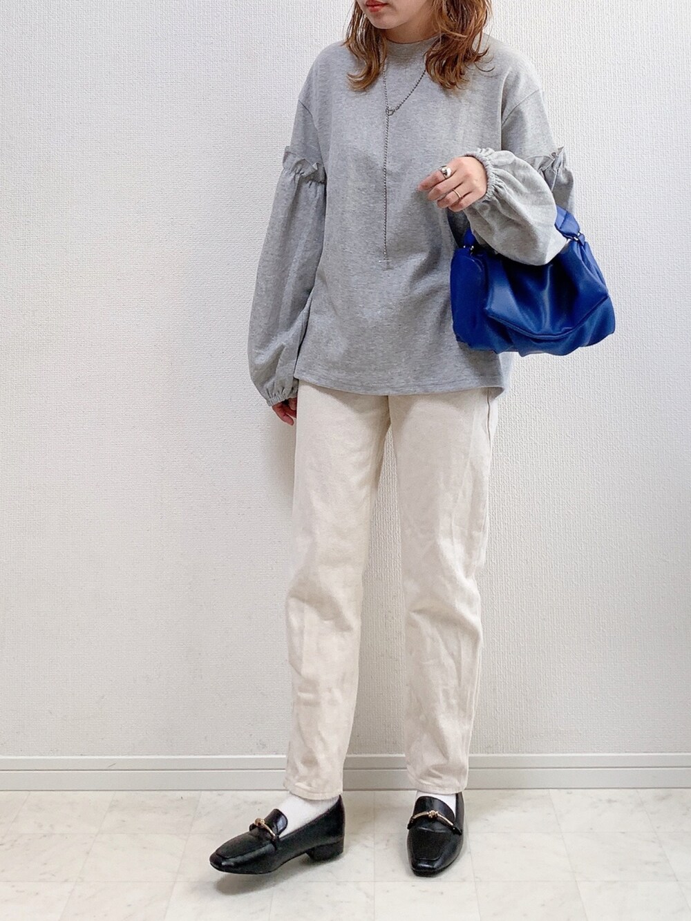 グレー系のTシャツ/カットソー、ブルー系のショルダーバッグ、ベージュ系のその他パンツを着用したレディースの冬コーディネートの2枚目の写真