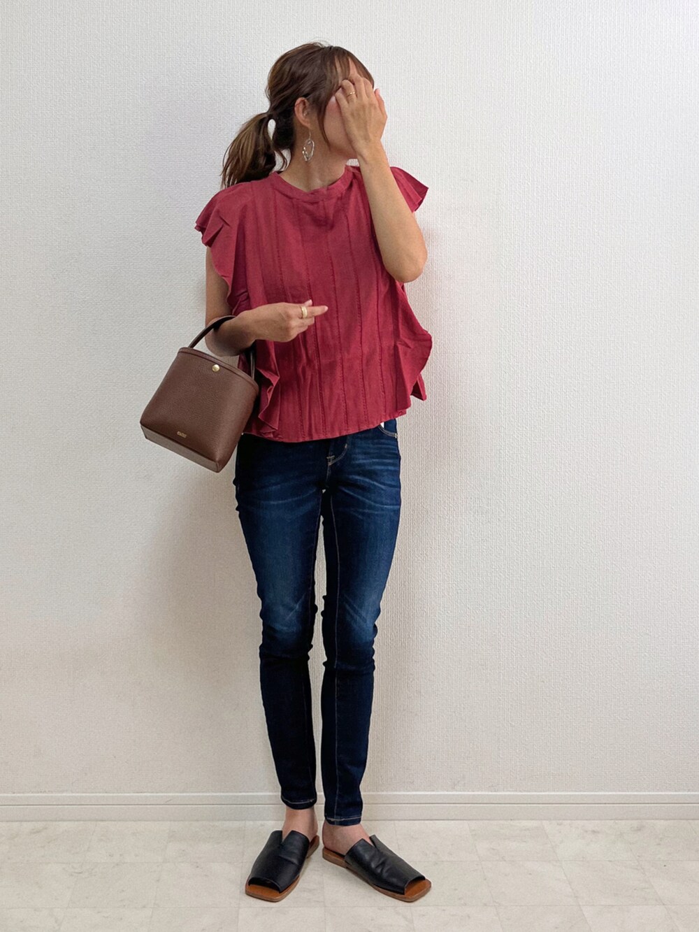 ピンク系のシャツ/ブラウス、ブルー系のデニムパンツ、ブラウン系のバッグを着用したレディースの夏コーディネートの2枚目の写真