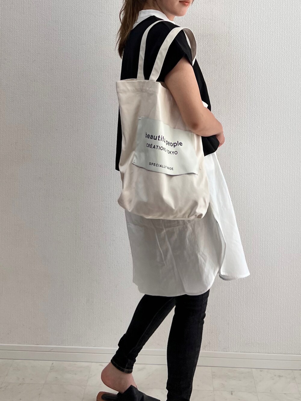 ブラック系のワンピース、ブラック系のデニムパンツ、ホワイト系のトートバッグを着用したレディースの夏コーディネートの2枚目の写真