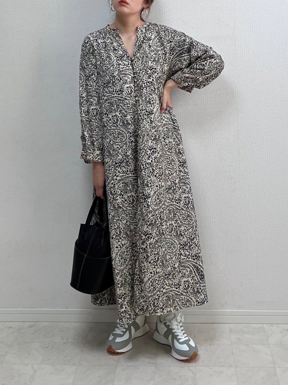 ブラック系のワンピース、ベージュ系のバッグを着用したレディースの春コーディネートの2枚目の写真