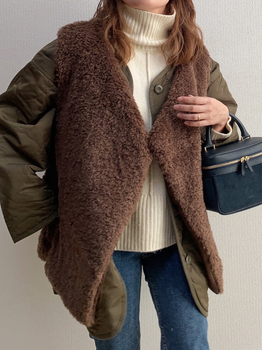グリーン系のノーカラージャケット、ブラウン系のベスト、ブルー系のハンドバッグを着用したレディースの冬コーディネートの2枚目の写真