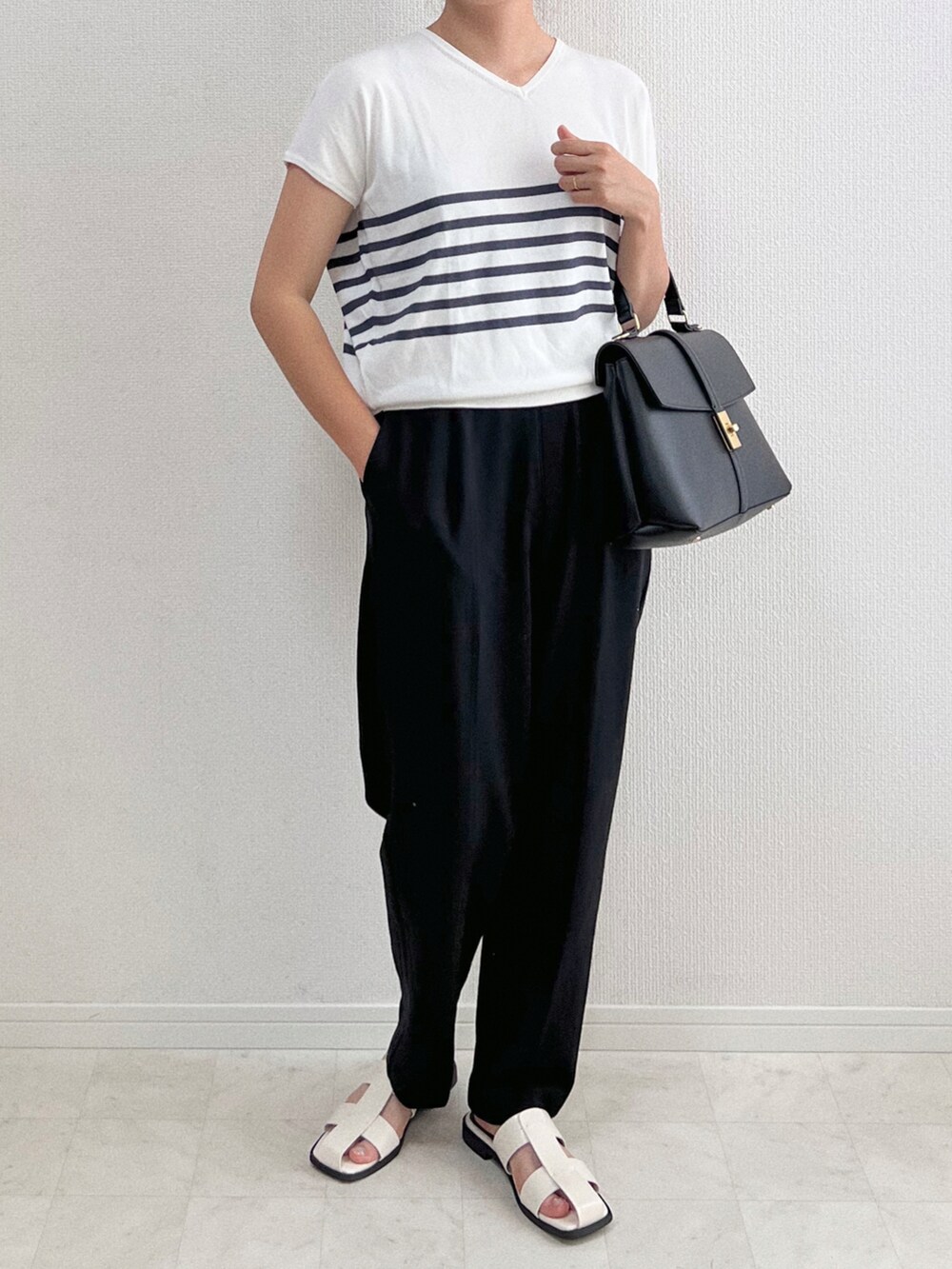 ホワイト系のTシャツ/カットソー、ブラック系のスラックス、ブラック系のバッグを着用したレディースの夏コーディネートの3枚目の写真