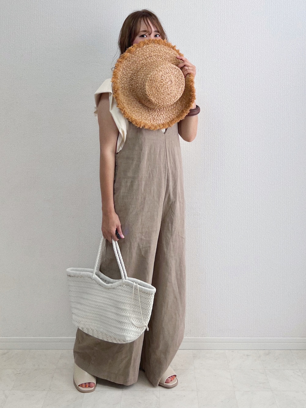 ベージュ系のサロペット/オーバーオール、ベージュ系のTシャツ/カットソー、ホワイト系のトートバッグを着用したレディースの夏コーディネートの3枚目の写真