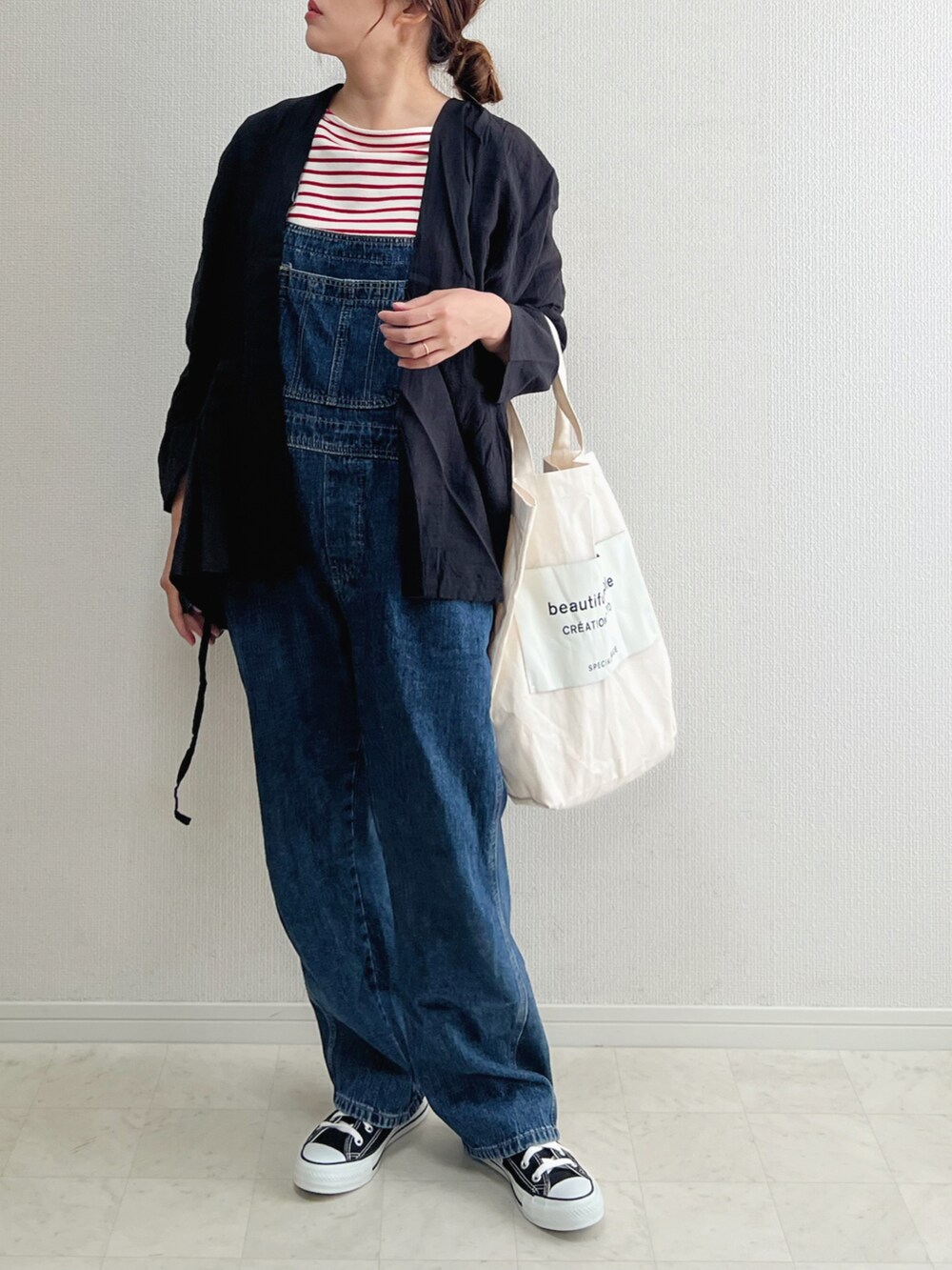 ブラック系のカーディガン/ボレロ、ブラック系のスニーカー、ブルー系のサロペット/オーバーオールを着用したレディースの春コーディネートの2枚目の写真