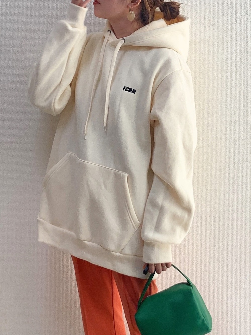 ベージュ系のパーカー、グリーン系のショルダーバッグ、オレンジ系のパンツを着用したレディースの春コーディネートの2枚目の写真