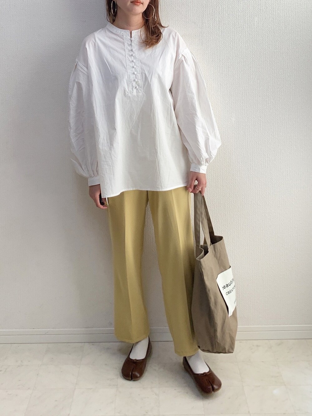 ホワイト系のシャツ/ブラウス、イエロー系のスラックス、ブラウン系のシューズを着用したレディースの冬コーディネートの2枚目の写真